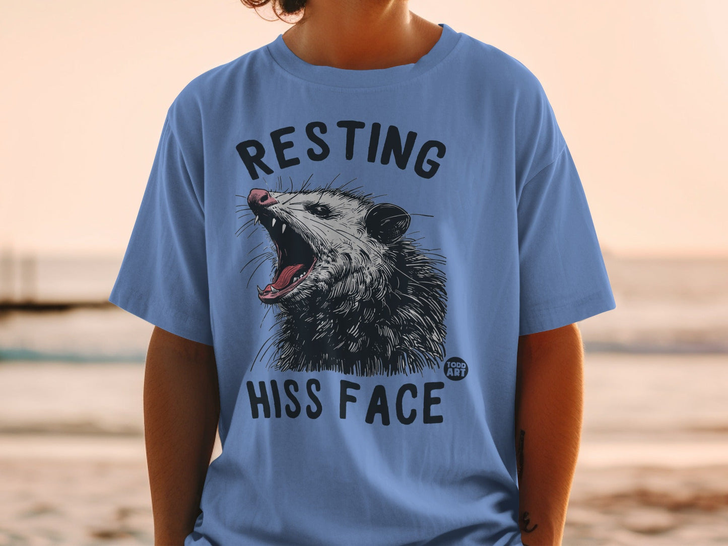 Blue t-shirt with opossum yawning and text "RESTING HISS FACE".