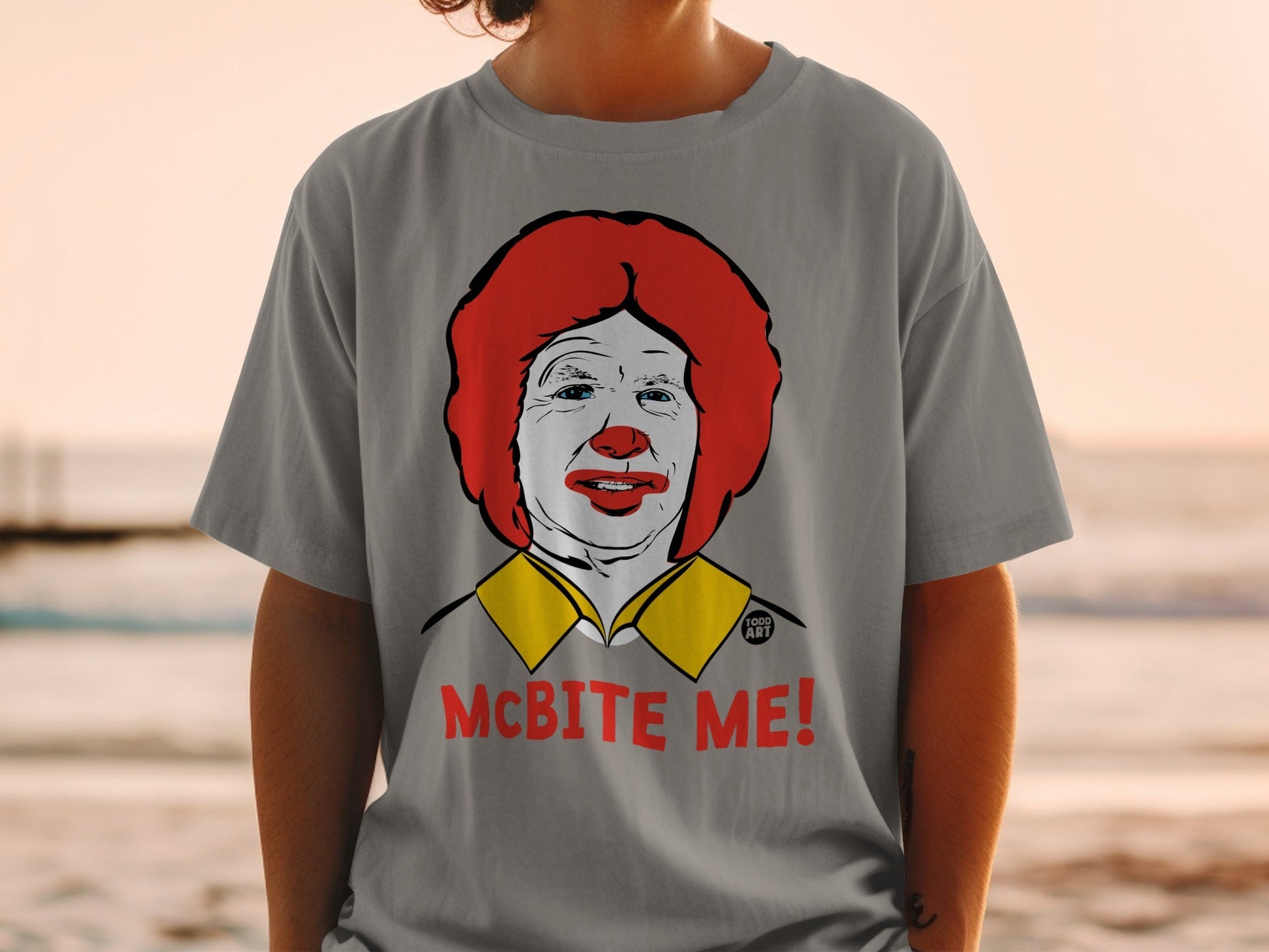 Gray t-shirt with a drawing of Ronald McDonald and the text "MCBITE ME!".