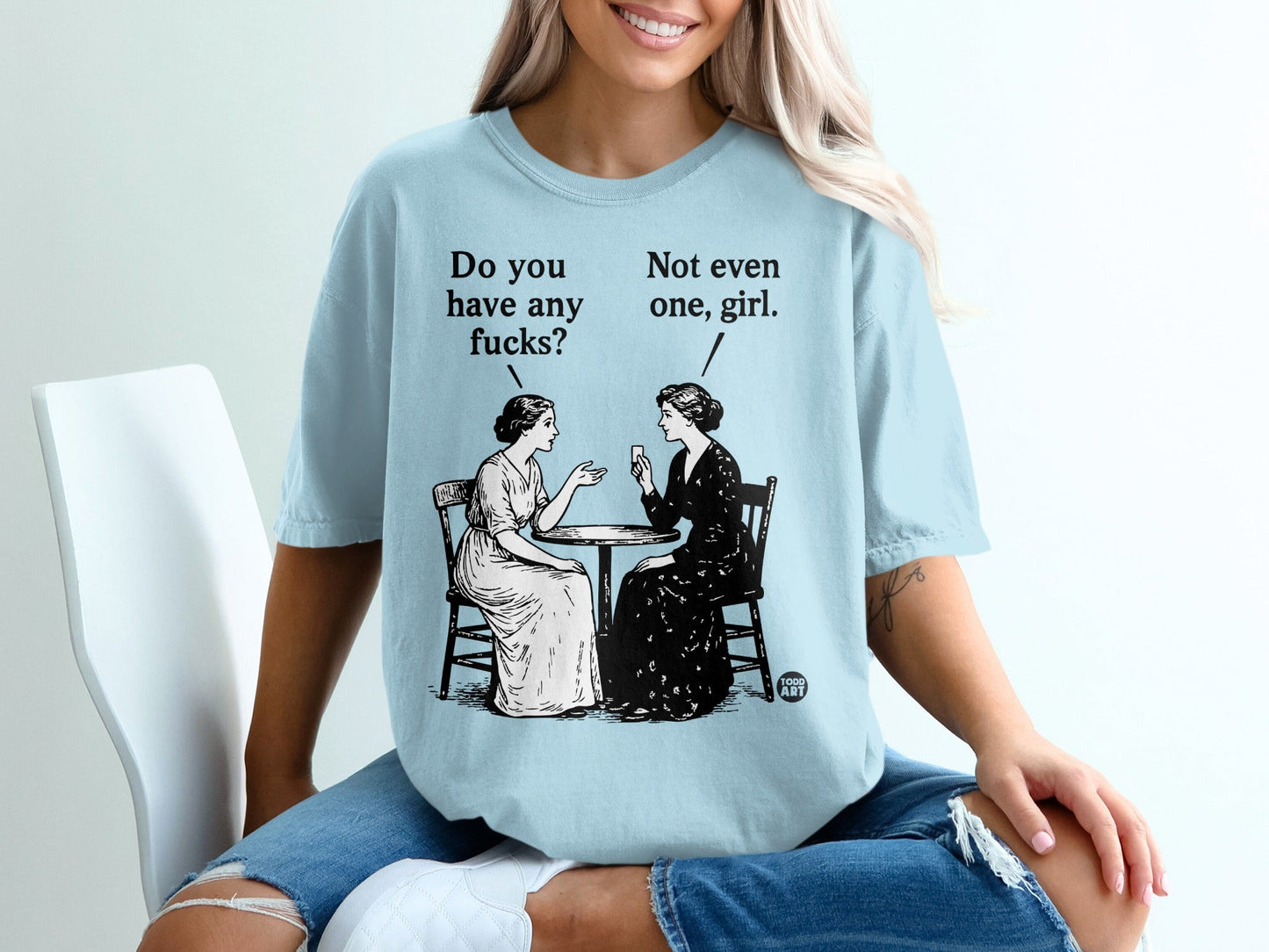 Two women sit at a table, one asking "Do you have any fucks?" the other replying "Not even one, girl."