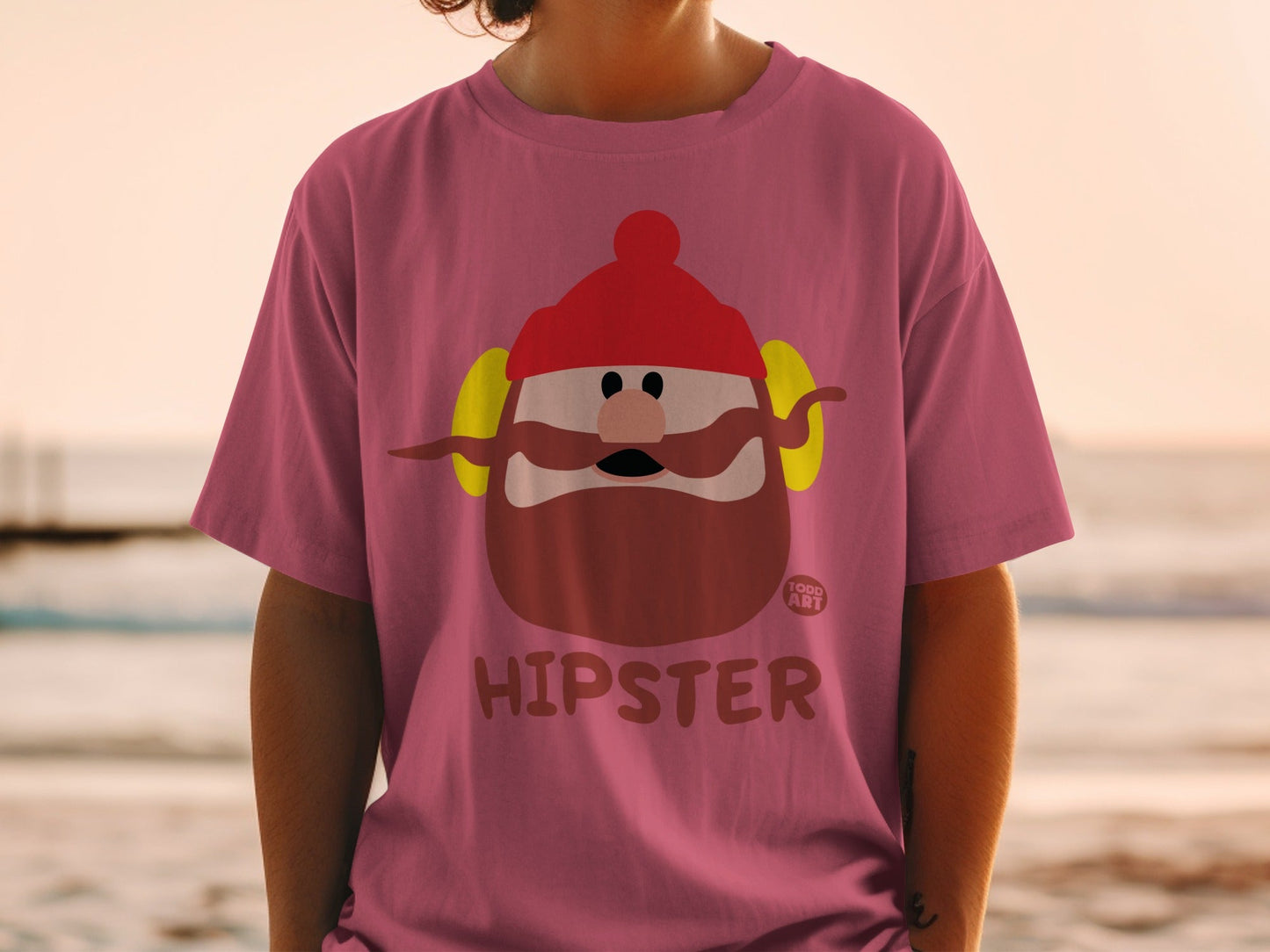 Pink t-shirt with cartoon man wearing hat and headphones, text "HIPSTER".