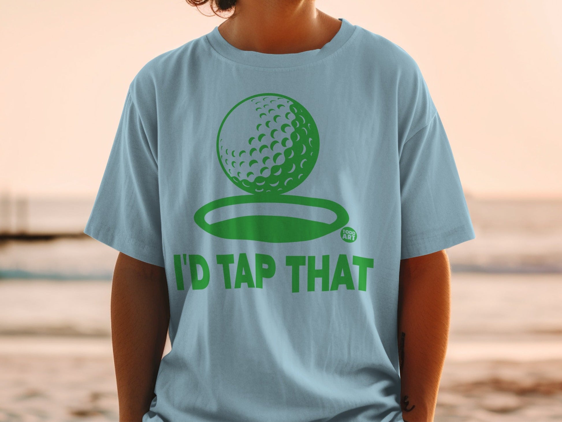 Light blue t-shirt with a green golf ball graphic and text "I'D TAP THAT".