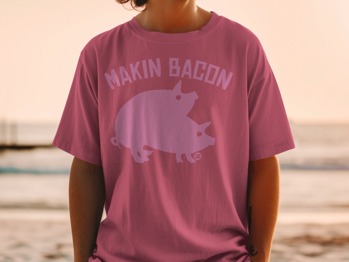 Pink t-shirt with "MAKIN' BACON" text and two pigs graphic.