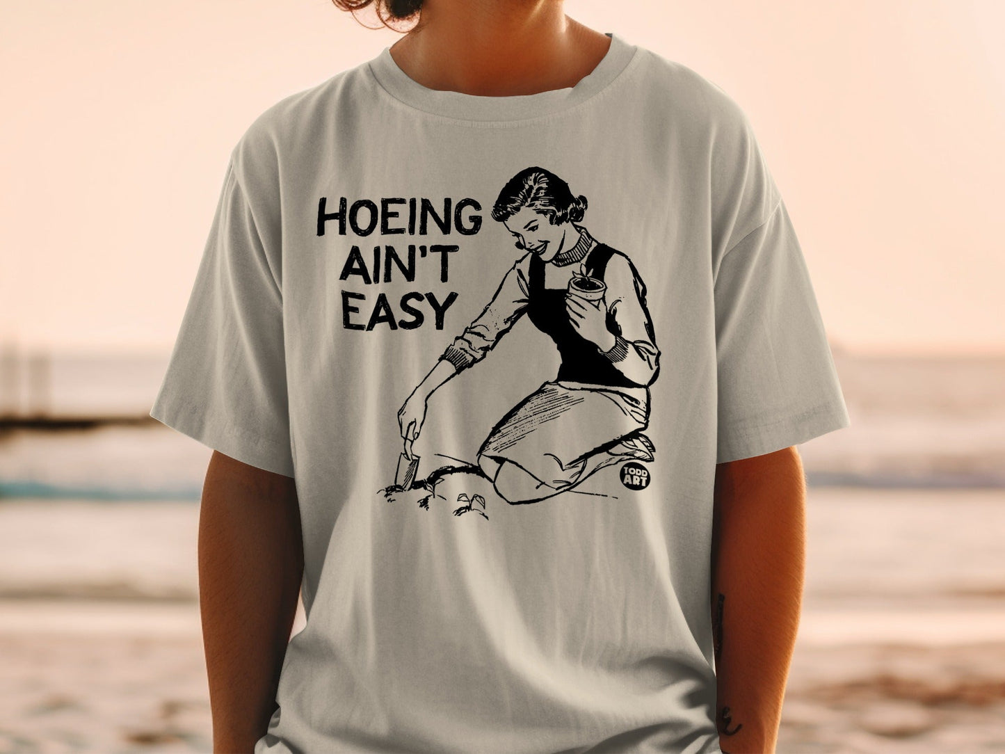 T-shirt with "Hoeing Ain't Easy" text and illustration of a woman gardening.