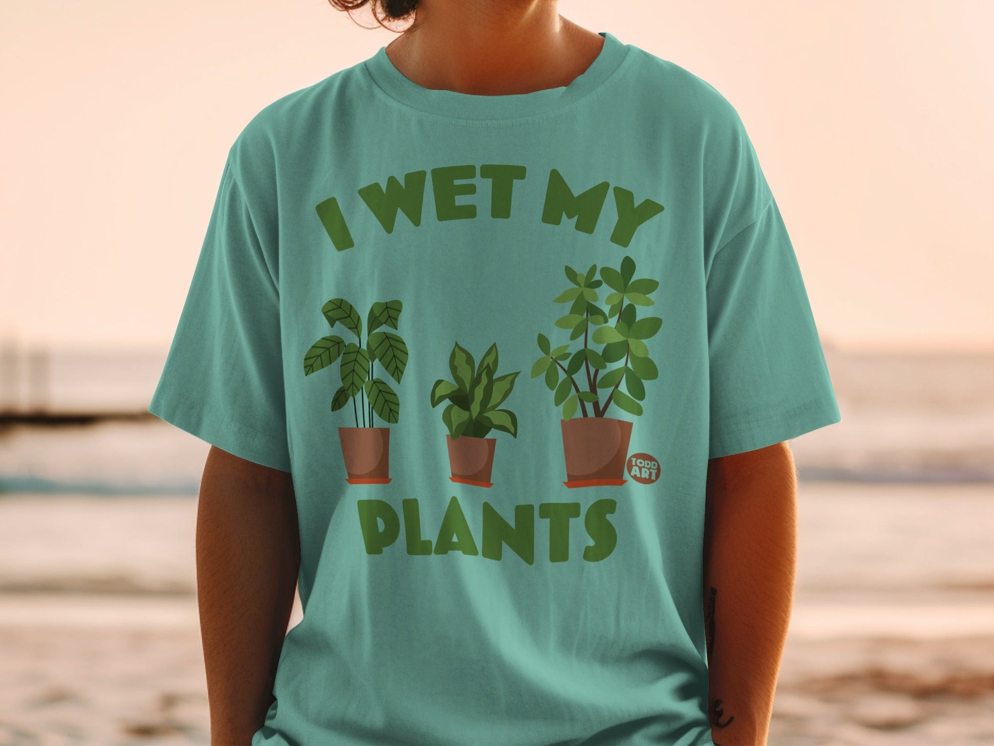 Teal t-shirt with "I WET MY PLANTS" and three potted plants.