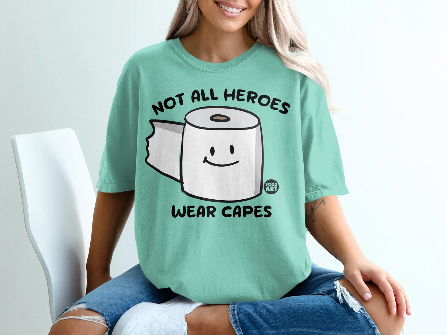 Mint t-shirt with cartoon toilet paper and text "Not all heroes wear capes."