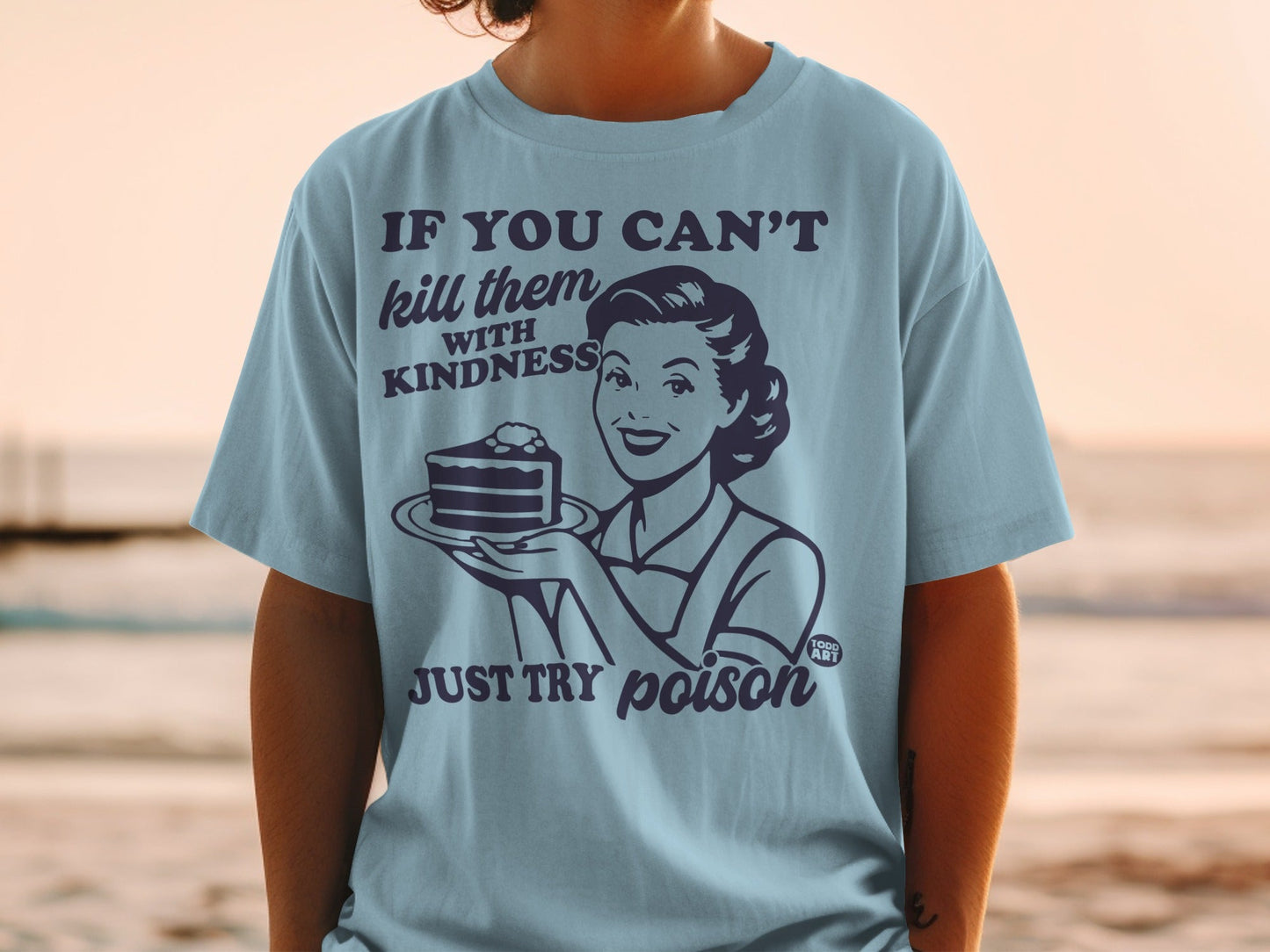 Light blue t-shirt with woman holding cake, text reads "kill them with kindness JUST TRY poison"