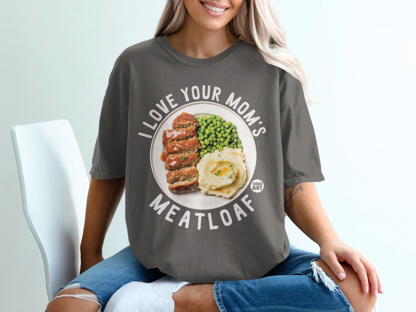 Woman wearing a t-shirt with "I LOVE YOUR MOM'S MEATLOAF" text and a meatloaf dinner graphic.