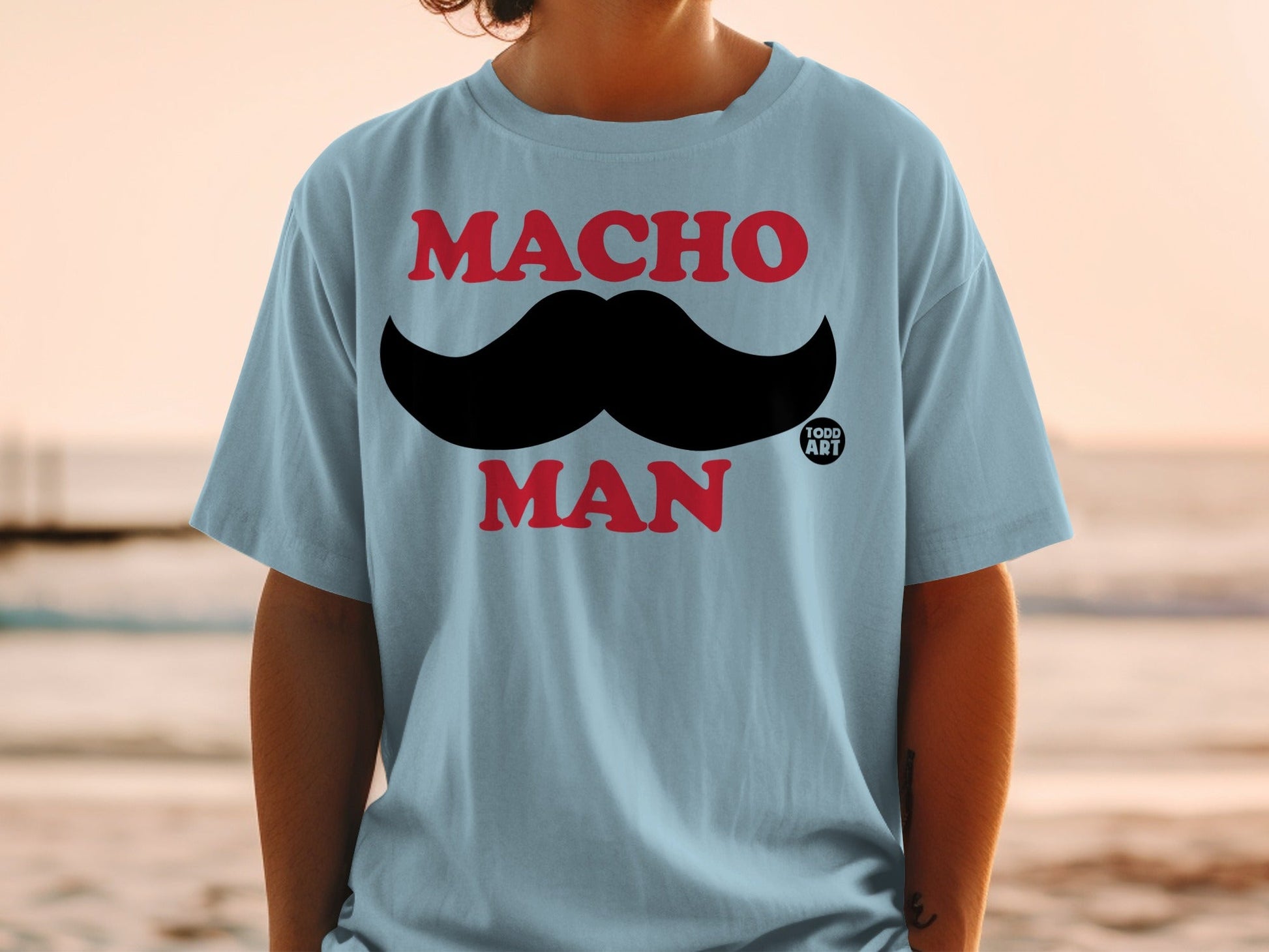 Light blue t-shirt with large black mustache and "MACHO MAN" text.