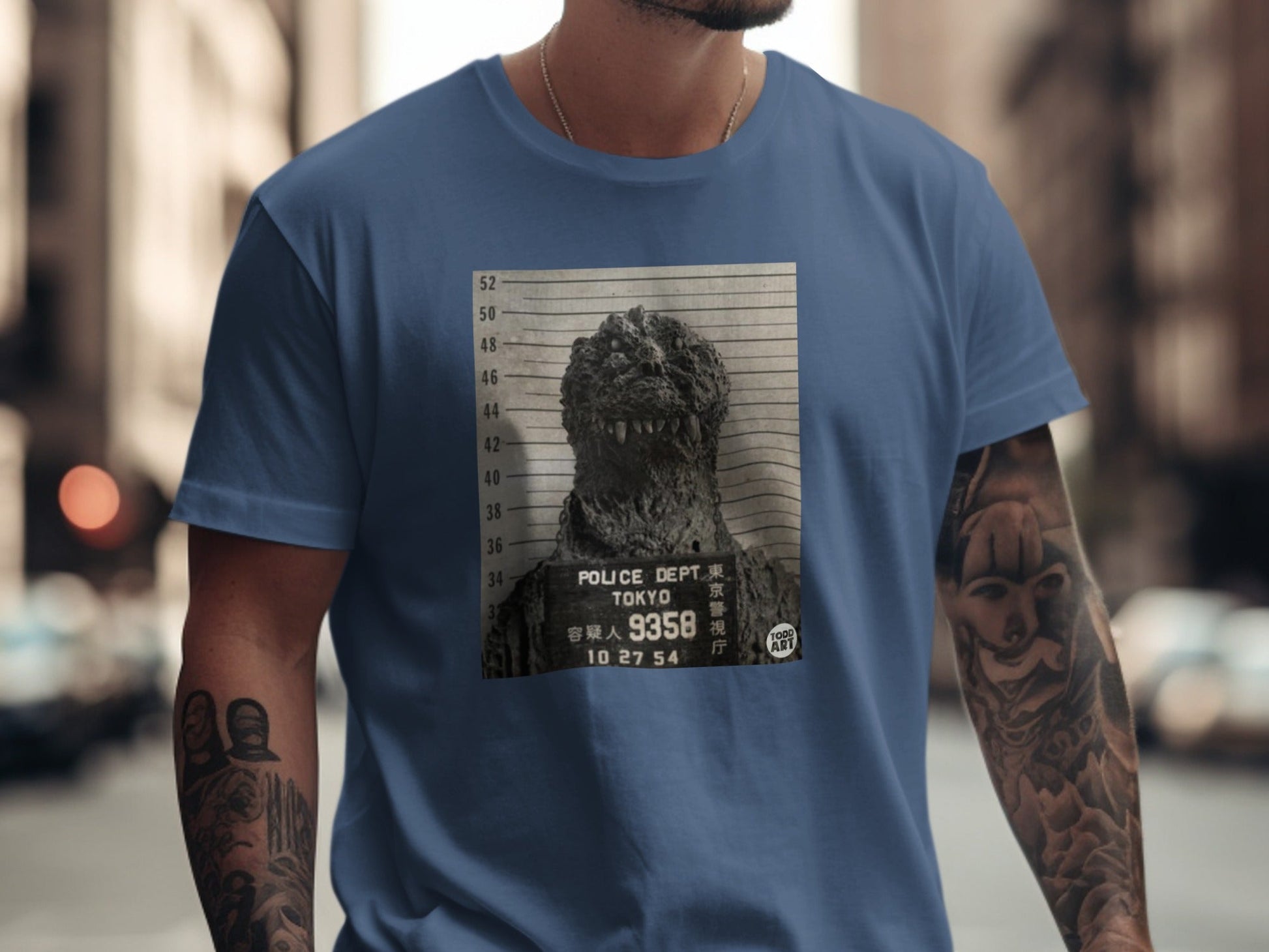Godzilla mugshot with "Tokyo Police Dept" and date on a navy blue t-shirt.