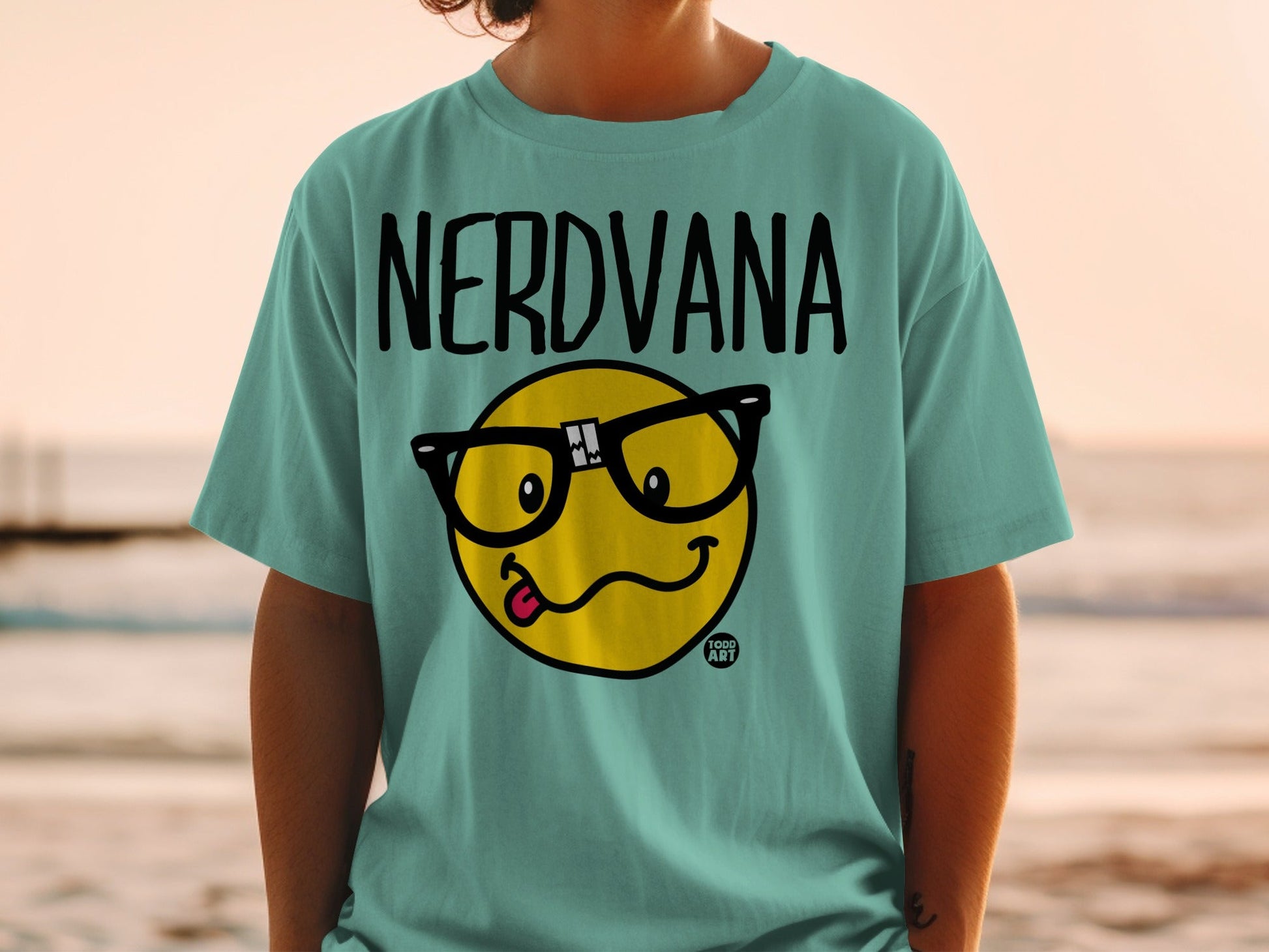Light teal t-shirt with "NERDVANA" and a smiling emoji with glasses.