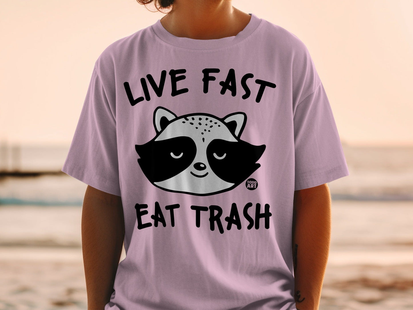 Purple t-shirt with a raccoon graphic and text "LIVE FAST EAT TRASH".