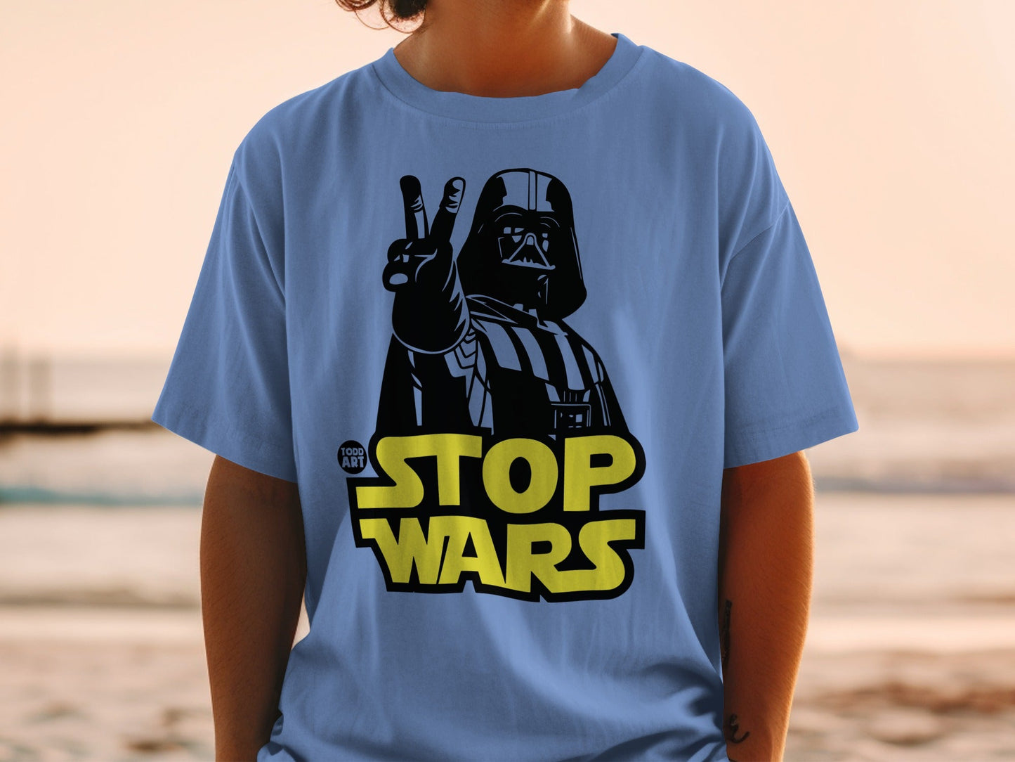 Darth Vader giving peace sign on blue t-shirt with "STOP WARS" text.