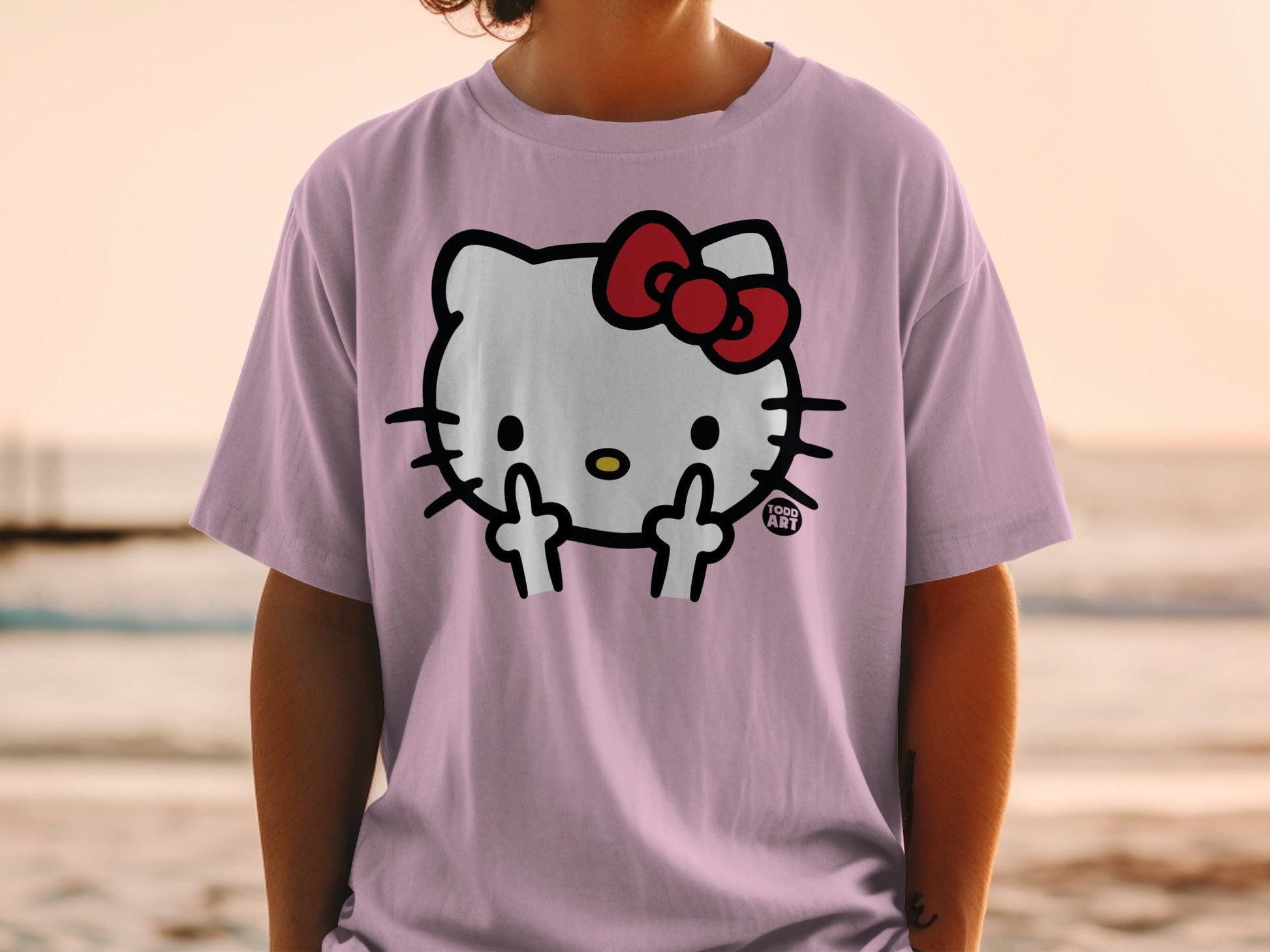 Hello Kitty t-shirt with middle fingers up, worn by person at beach.