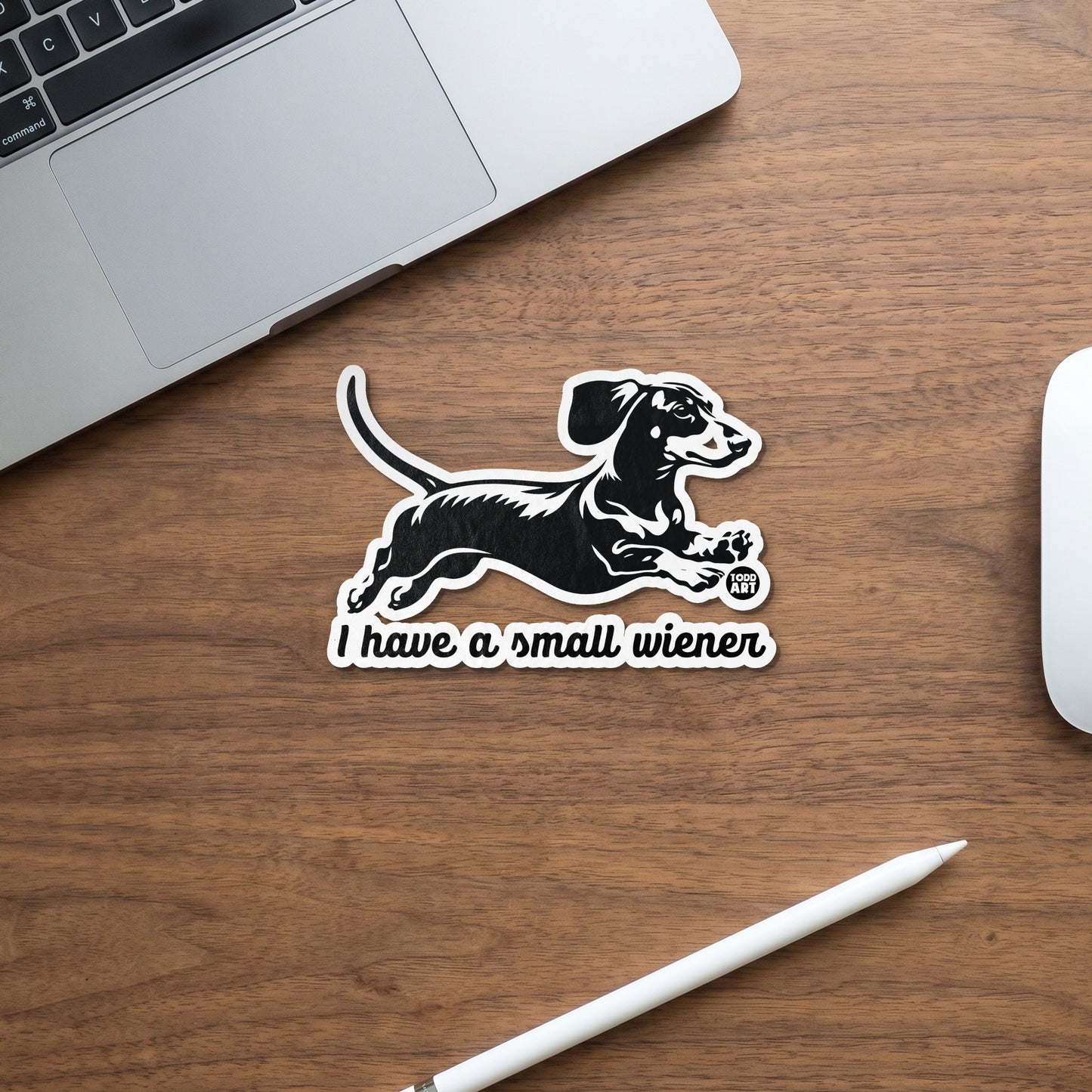 Black and white sticker of a dachshund running with text "I have a small wiener".