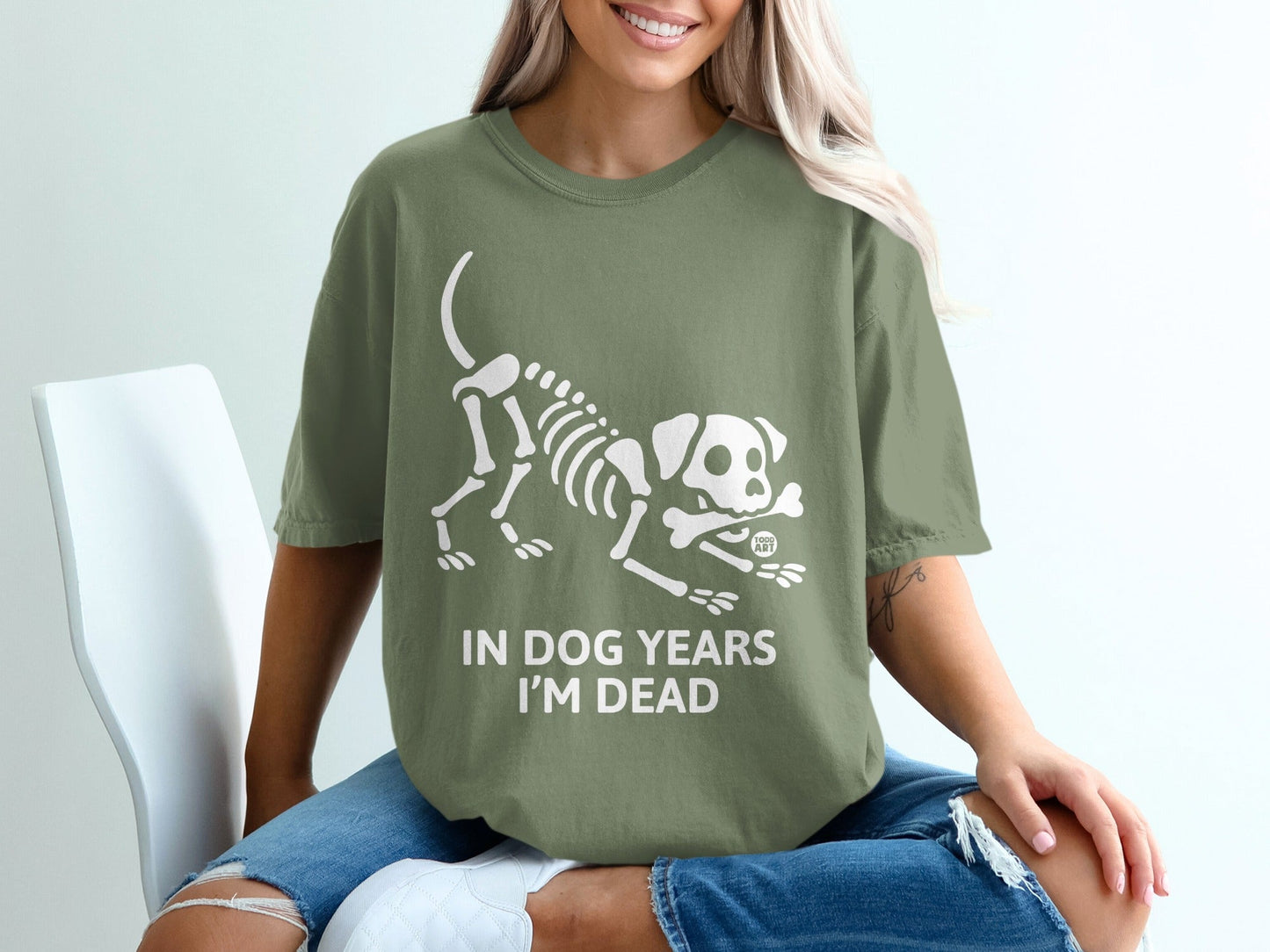 Olive green t-shirt with white dog skeleton graphic and "IN DOG YEARS I'M DEAD" text.