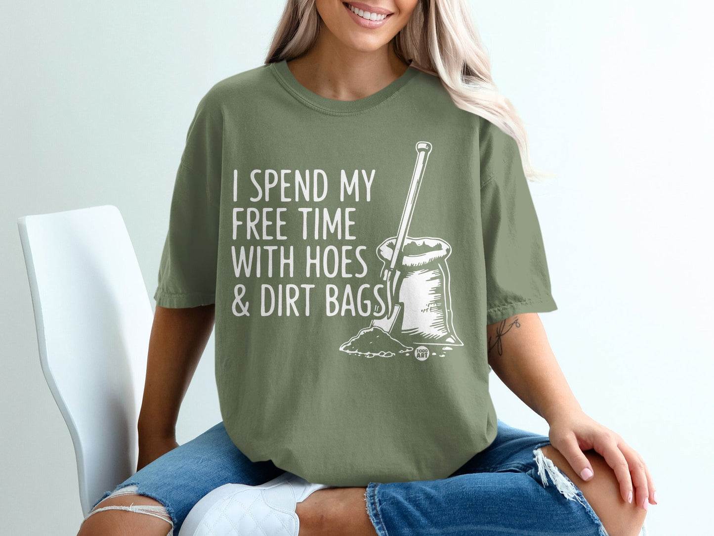 Green t-shirt with text "I spend my free time with hoes & dirt bags" and shovel in dirt.