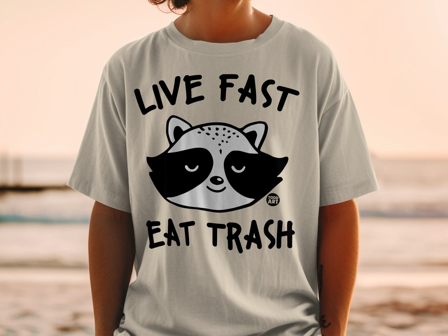 T-shirt with raccoon graphic and "LIVE FAST EAT TRASH" text.