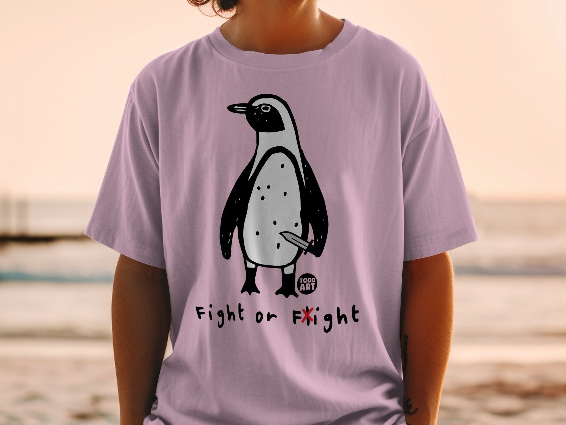 Penguin with knife graphic on a pink t-shirt with "Fight or Flight" text.