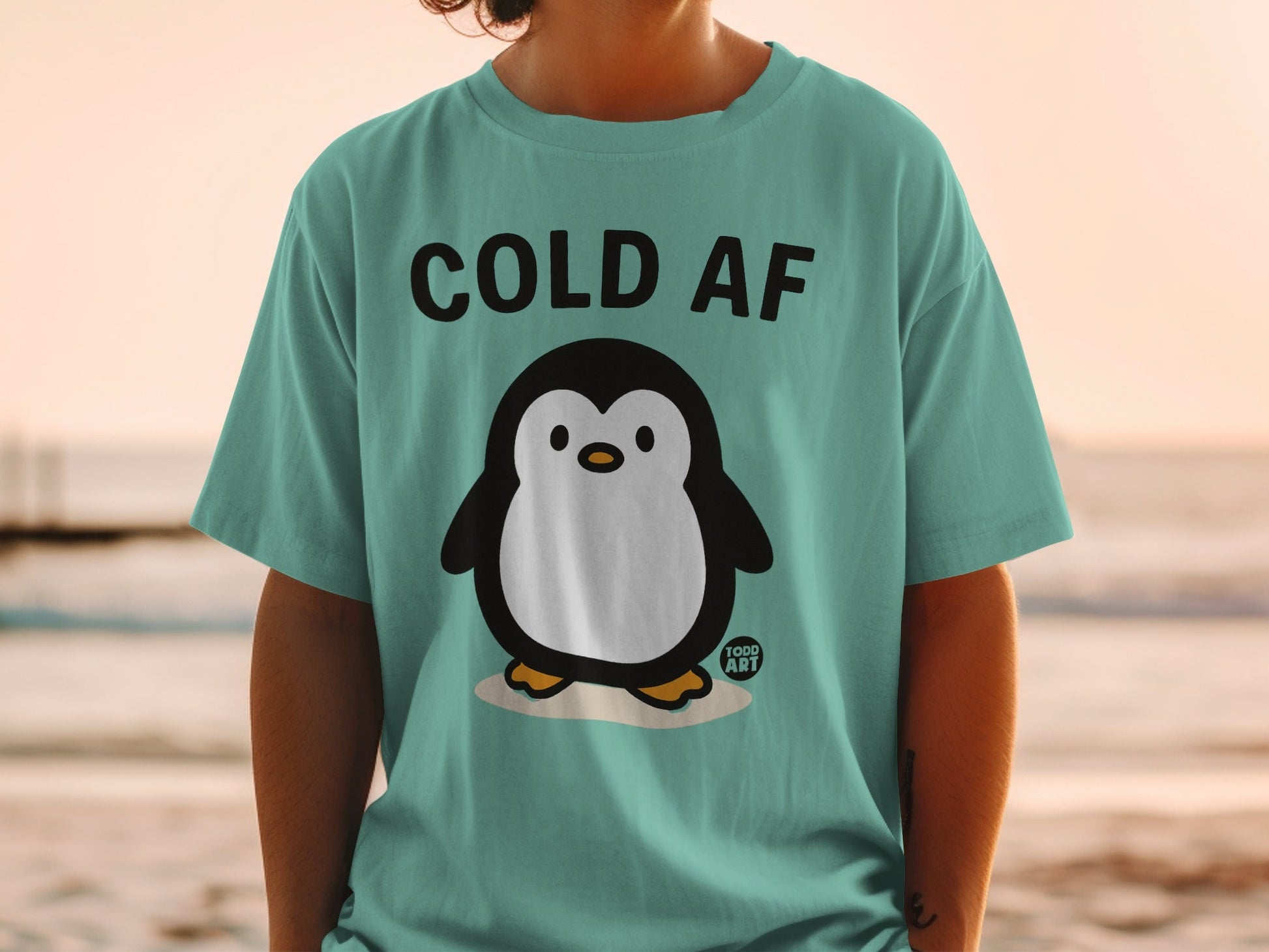 Teal t-shirt with a cartoon penguin and text "COLD AF".