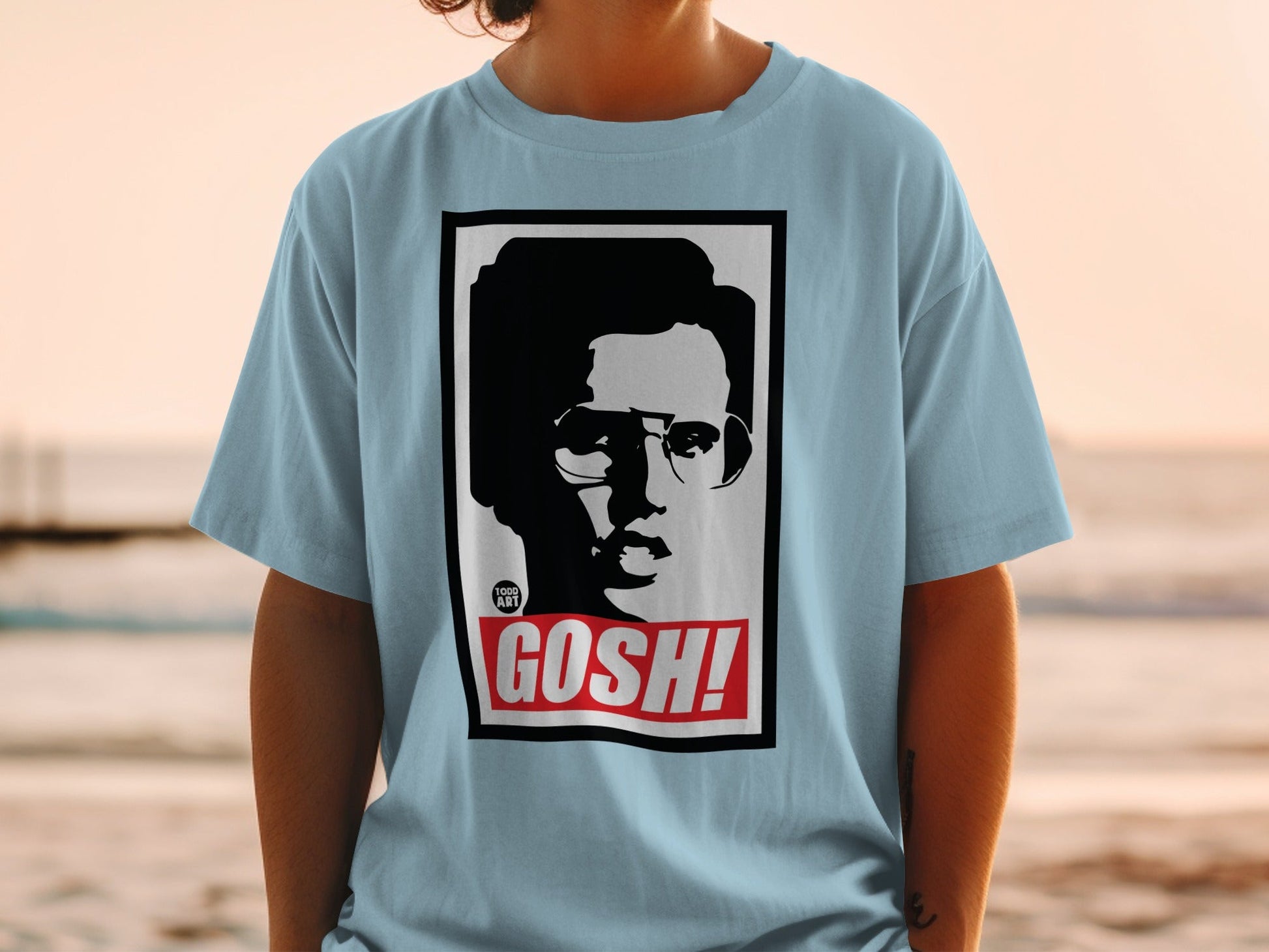 Light blue t-shirt with black and white portrait and "GOSH!" text.