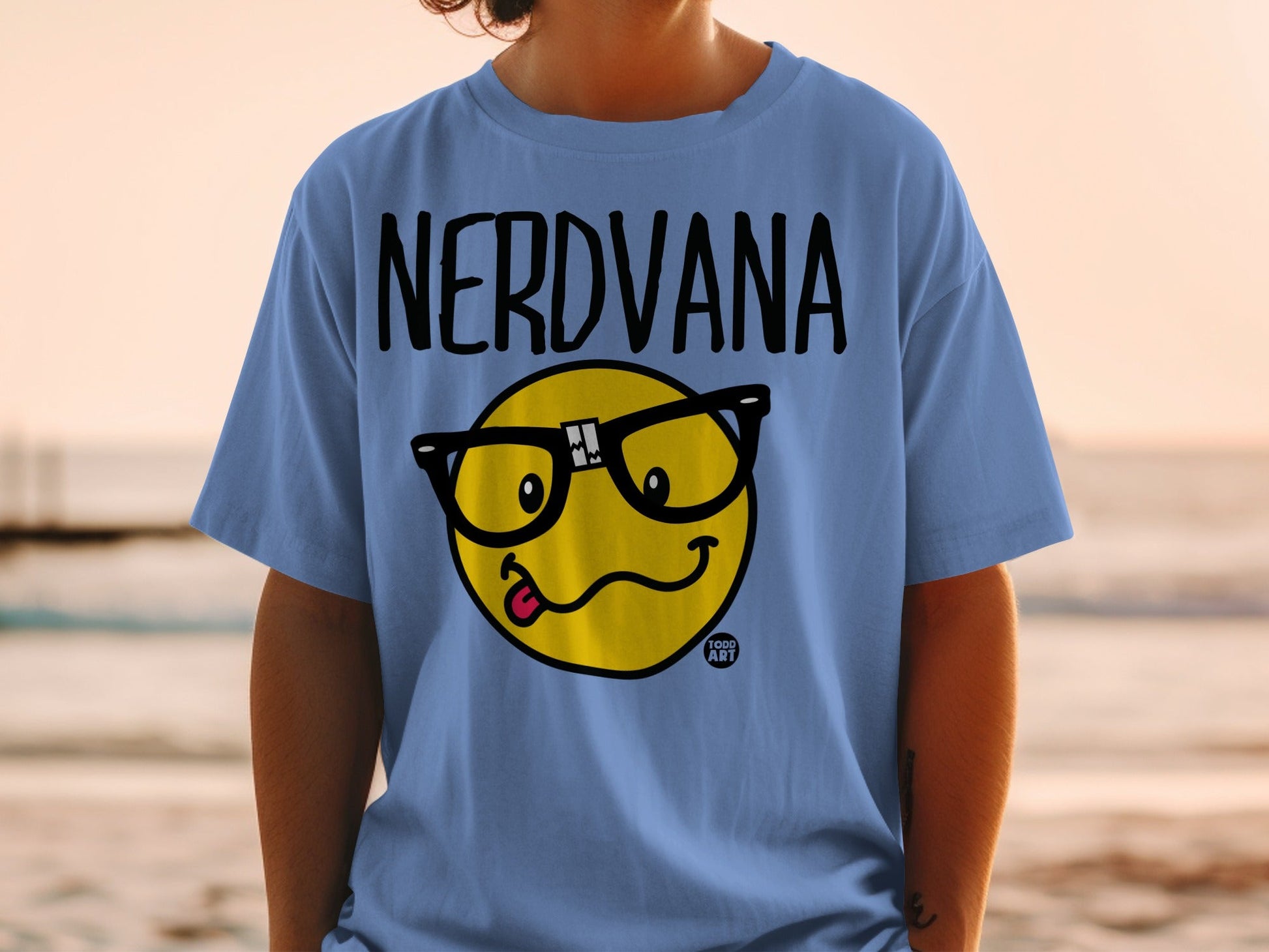 Blue t-shirt with black "NERDVANA" text and a yellow emoji with glasses and tongue out.