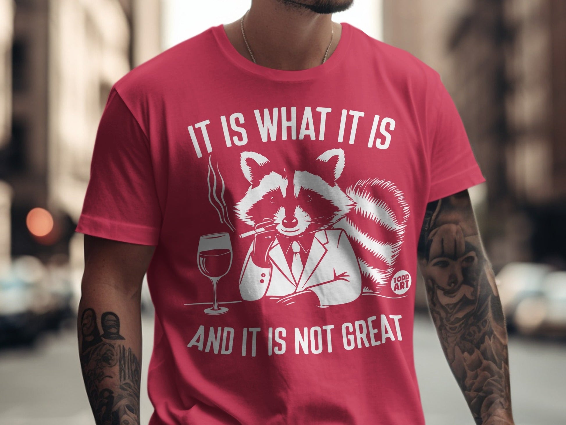 Red t-shirt with raccoon in suit smoking and saying "It is what it is and it is not great".