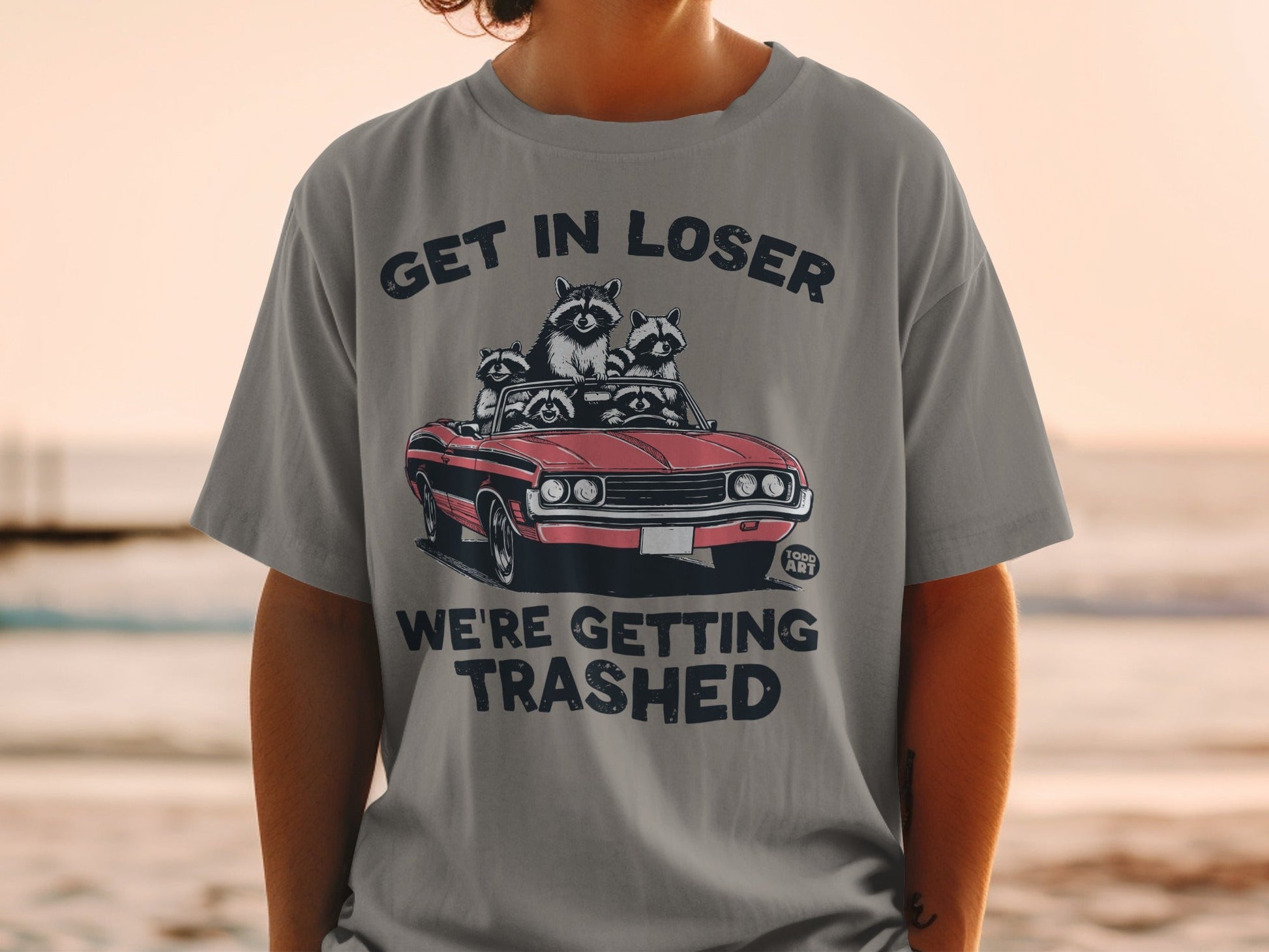 T-shirt with raccoons in a convertible and text "GET IN LOSER WE'RE GETTING TRASHED".