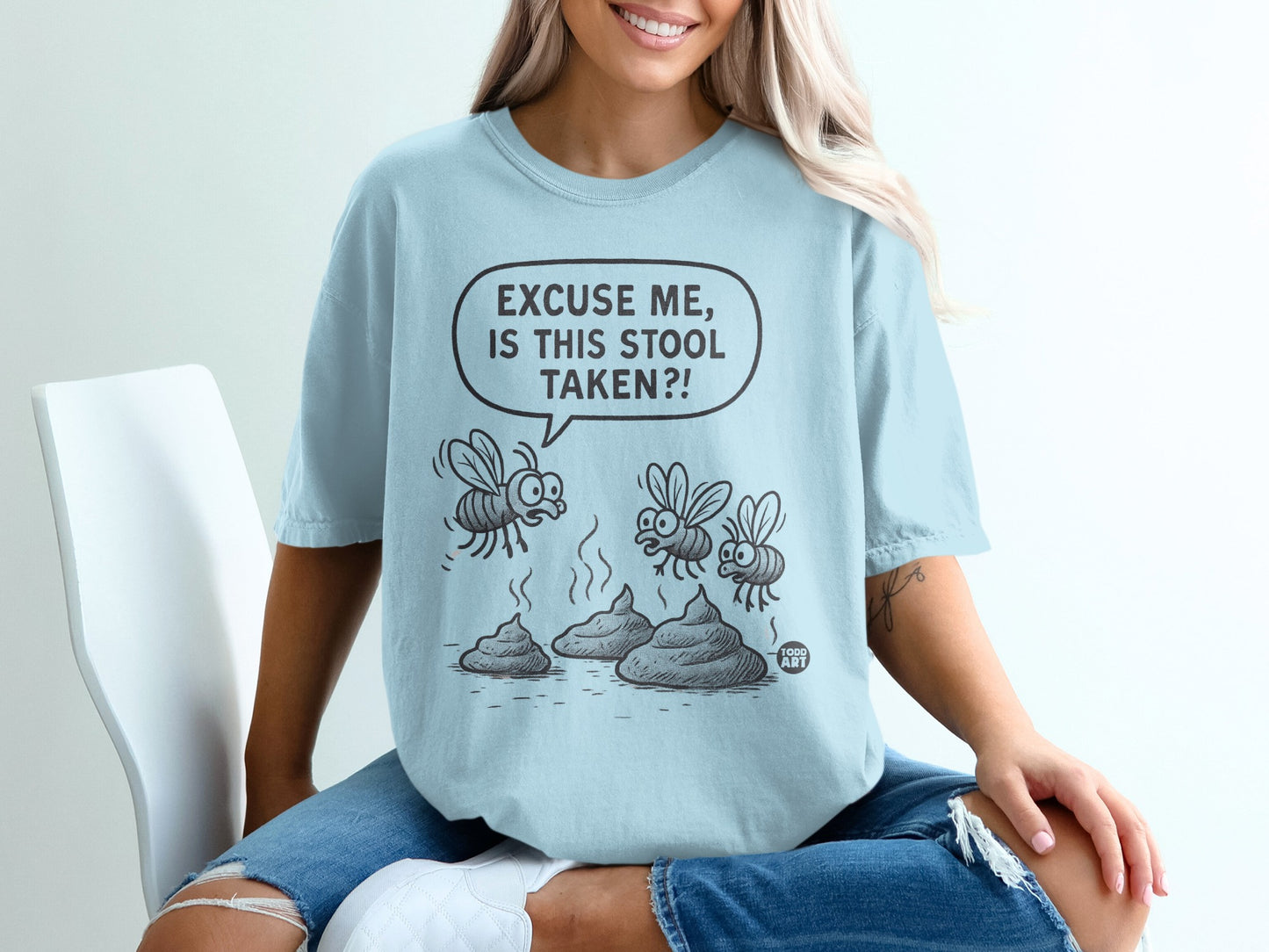 Light blue t-shirt with cartoon flies on poop and text "Excuse me, is this stool taken?!"