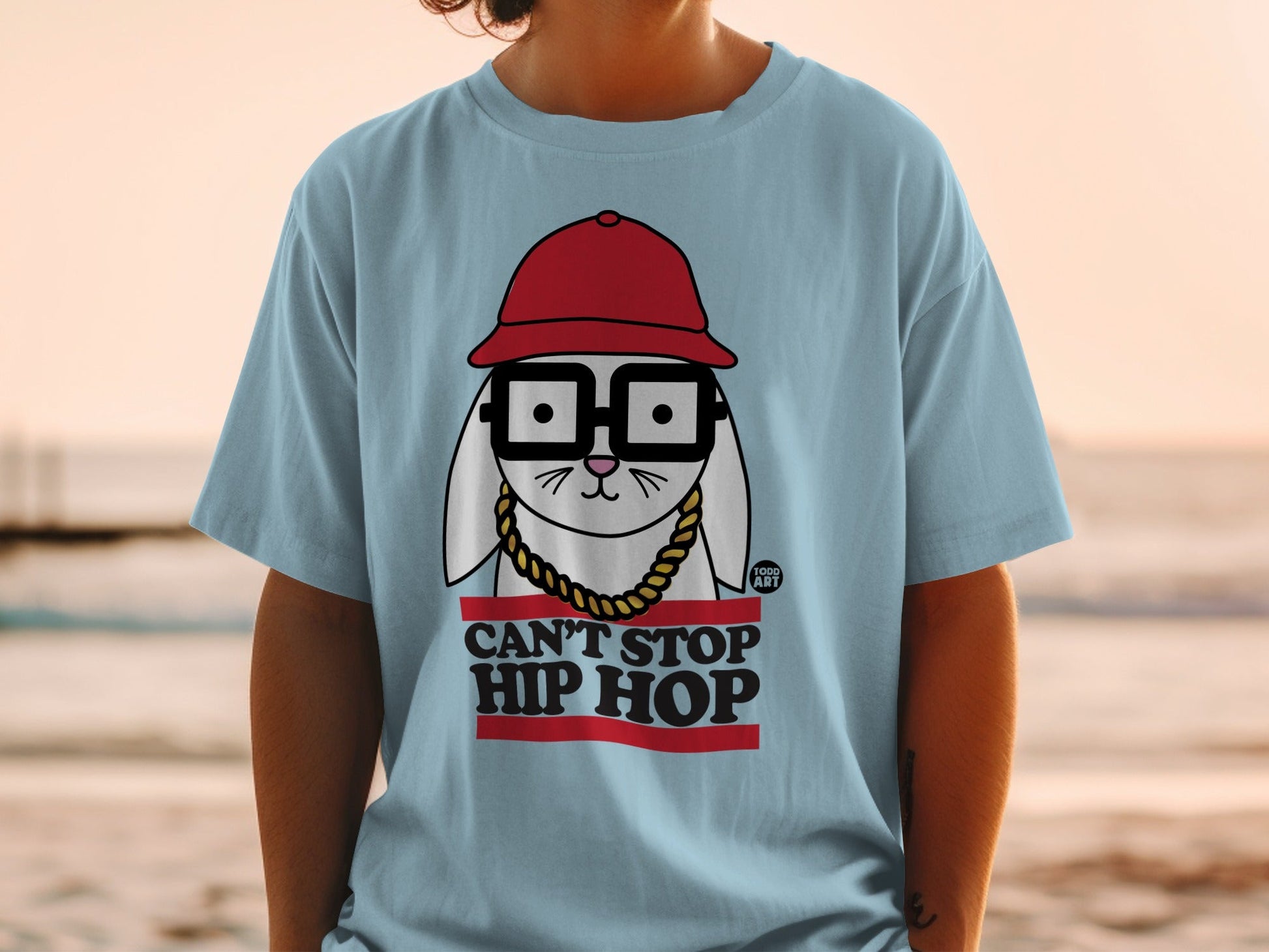 Light blue t-shirt with a graphic of a rabbit wearing glasses, a red hat, and a gold chain.