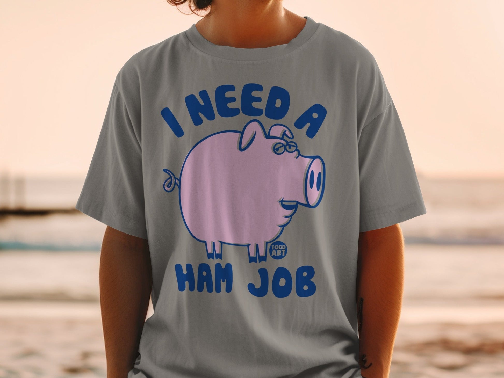 Grey t-shirt with a cartoon pig wearing glasses and the text "I NEED A HAM JOB".