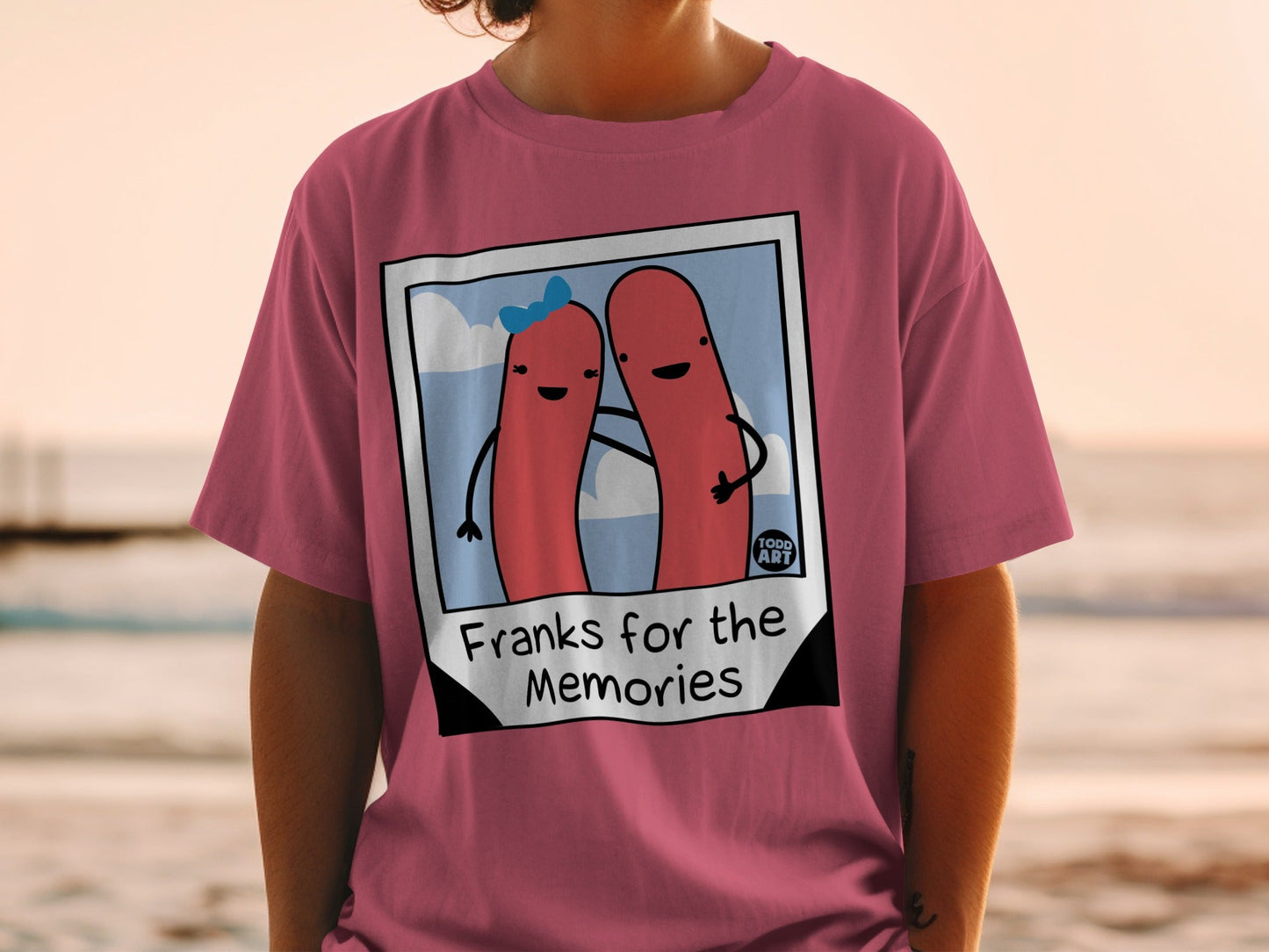 Pink t-shirt with cartoon hot dogs and text "Franks for the Memories".