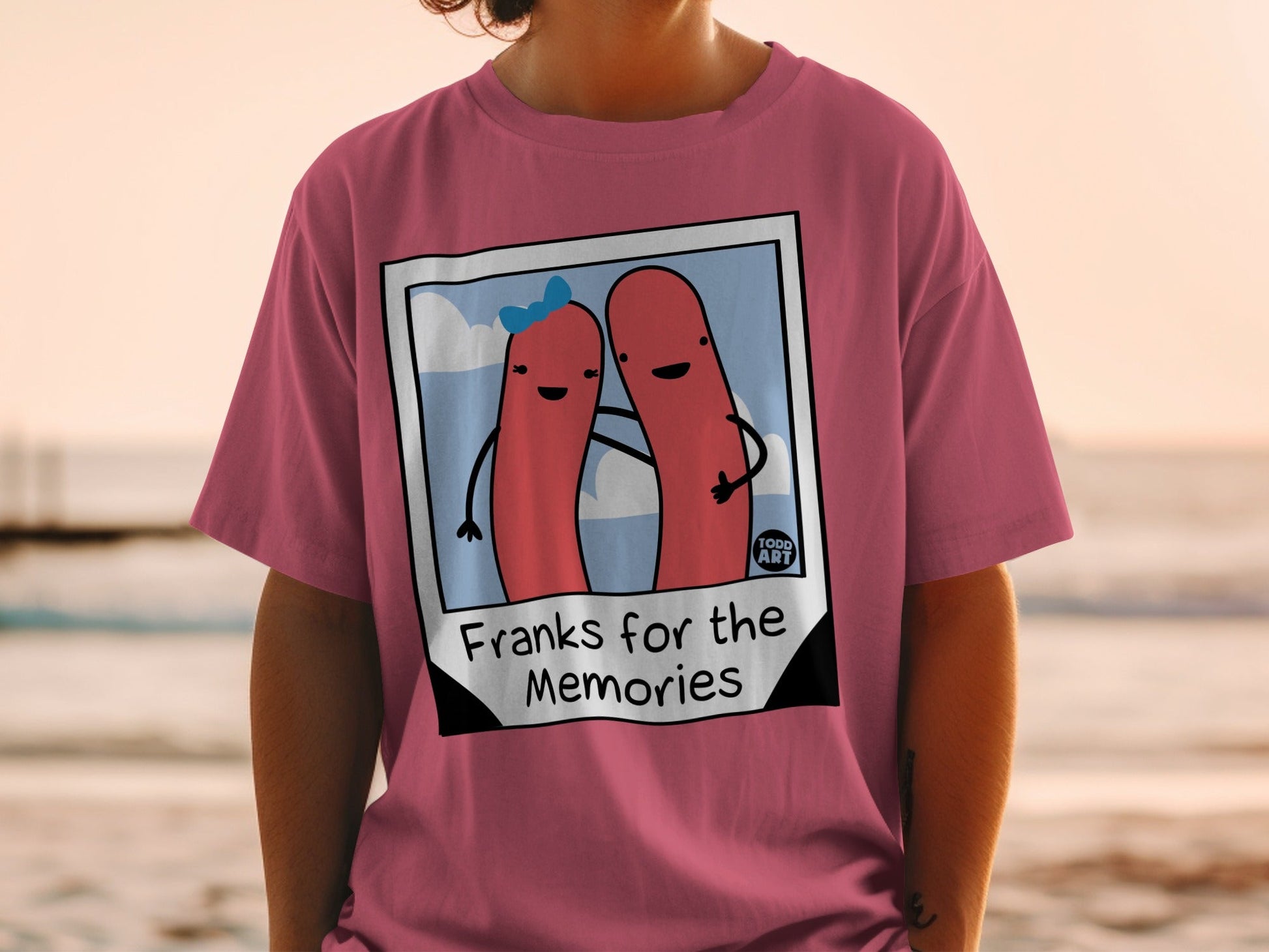 Pink t-shirt with cartoon hot dogs and text "Franks for the Memories".