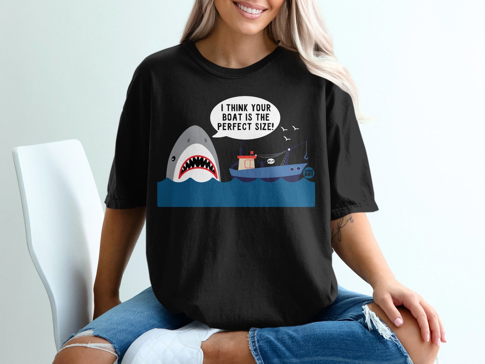 Black t-shirt with cartoon shark and fishing boat graphic.