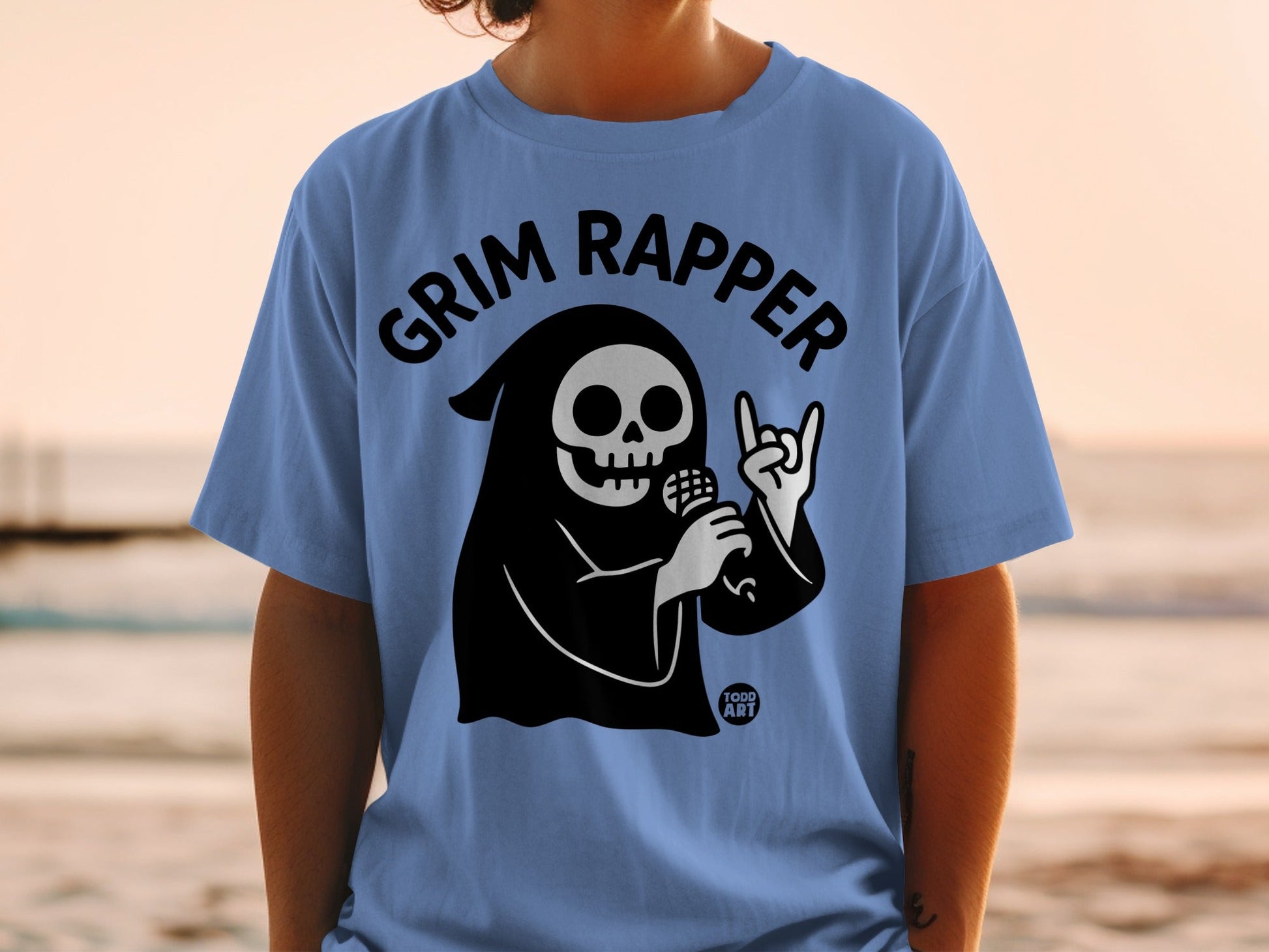 Grim Reaper in a black robe holds a microphone and makes a rock on gesture.