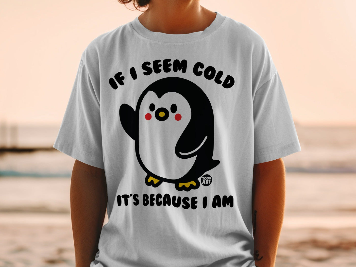 White t-shirt with a cartoon penguin and text "IF I SEEM COLD IT'S BECAUSE I AM".
