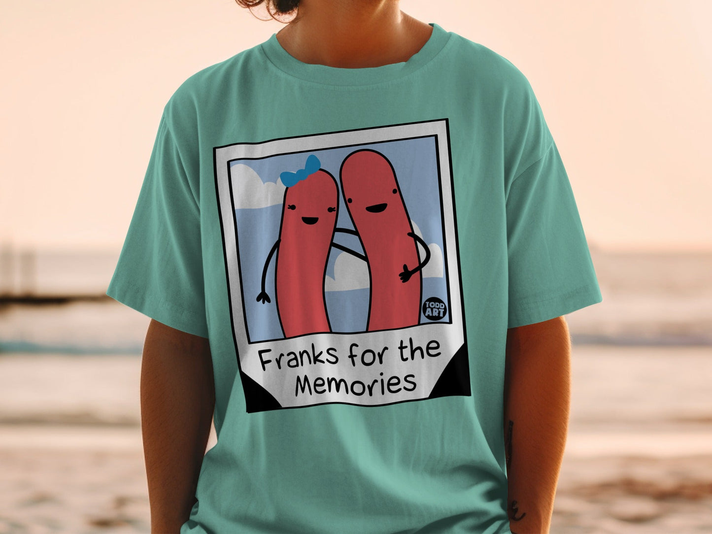 Teal t-shirt with cartoon hot dogs and "Franks for the Memories" text.