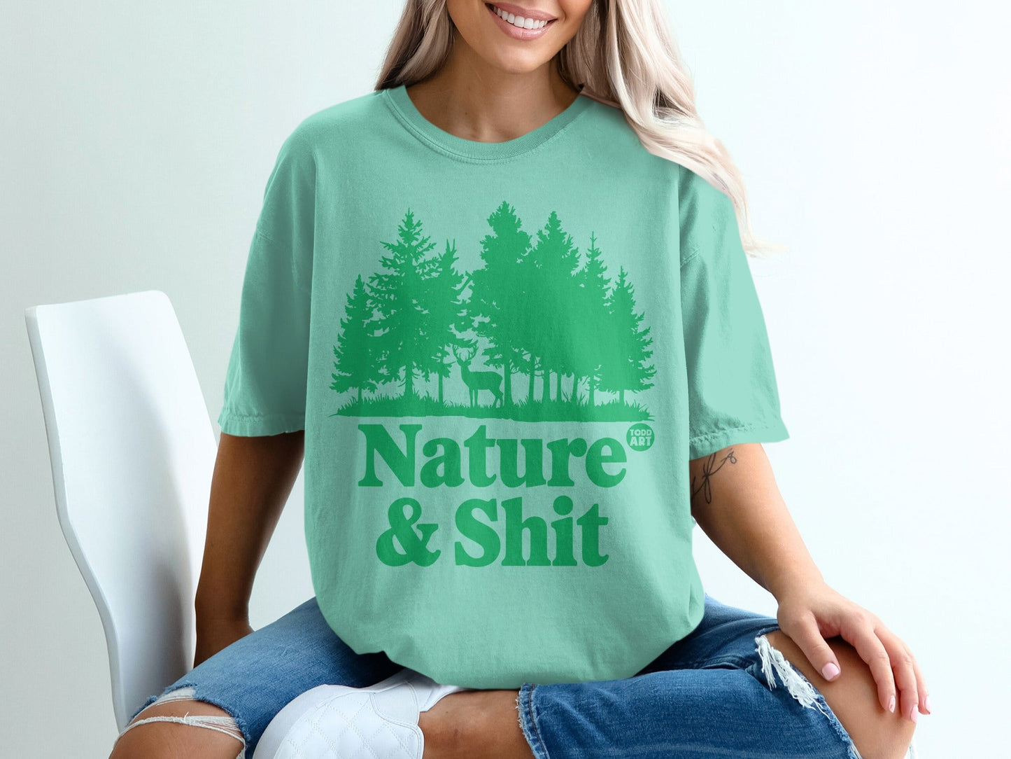 Teal t-shirt with green pine trees and "Nature & Shit" text.