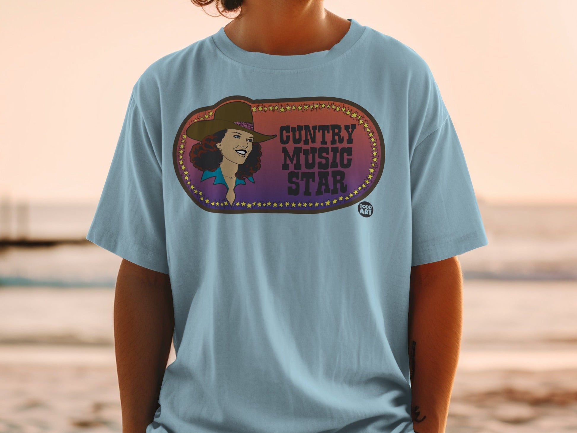 Country Music Star graphic on light blue t-shirt with colorful oval design.