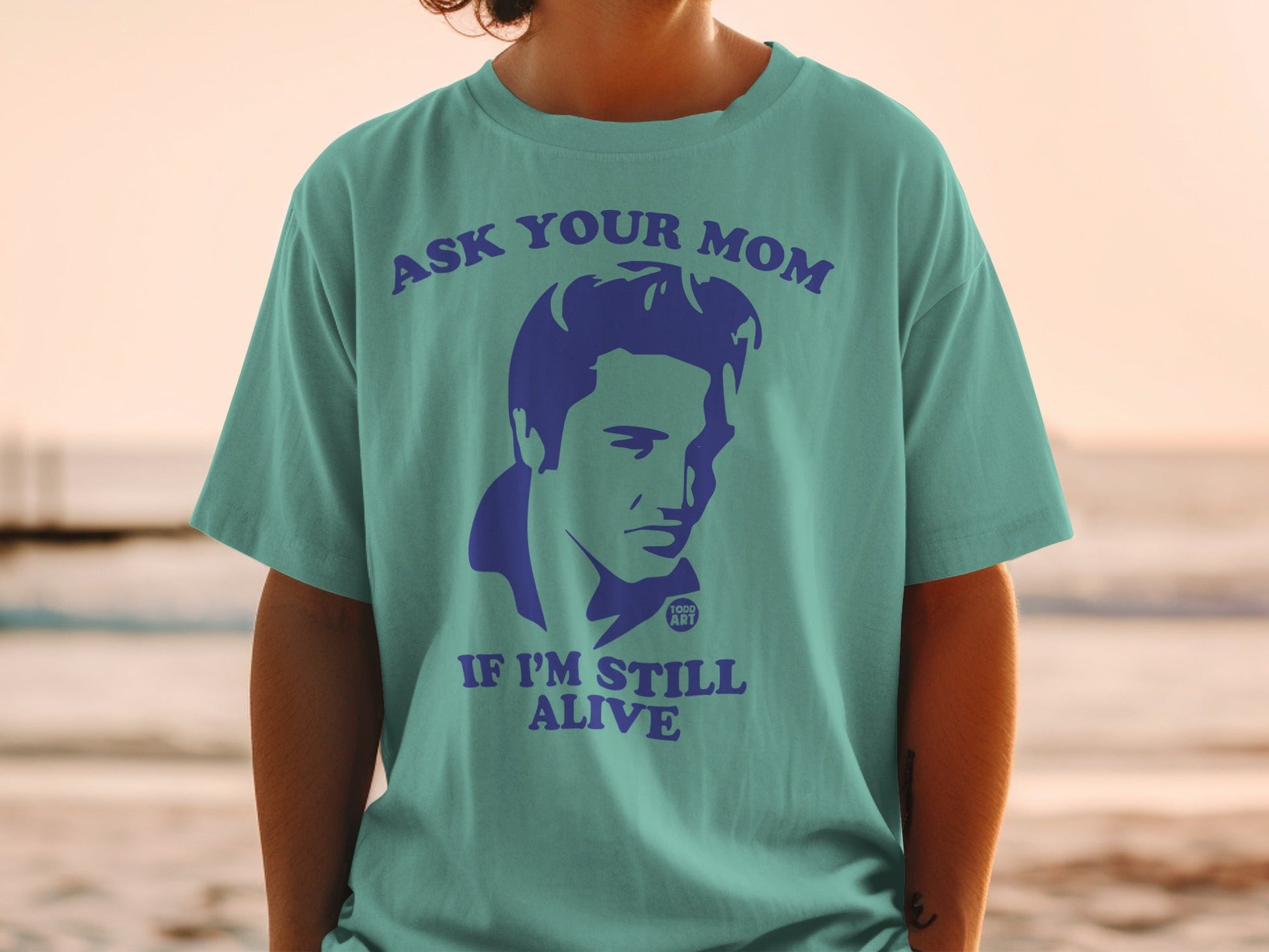 Teal t-shirt with Elvis Presley graphic and text "ASK YOUR MOM IF I'M STILL ALIVE".