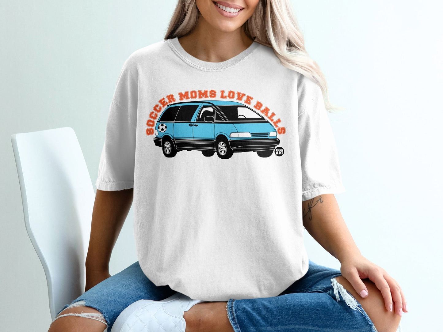 Blue minivan graphic with text "Soccer Moms Love Balls" on a white t-shirt.
