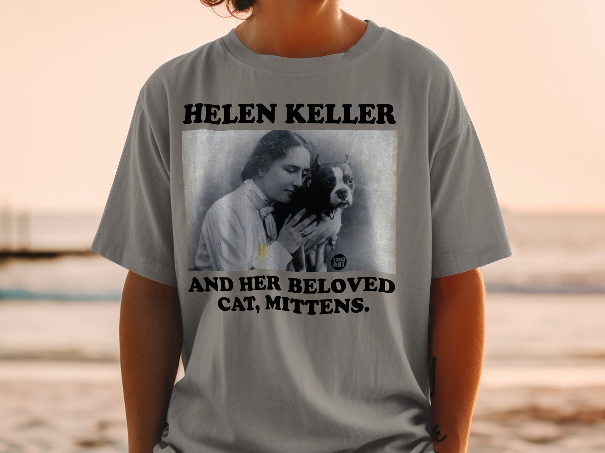 T-shirt featuring Helen Keller holding a cat, with text.