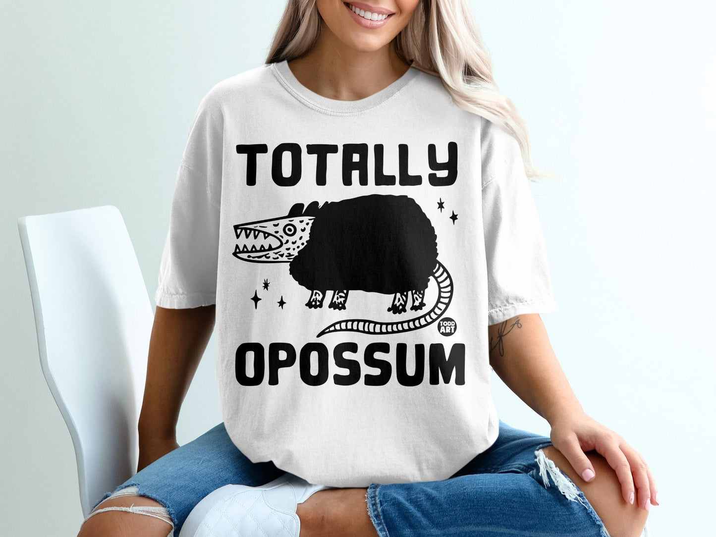 White t-shirt with "TOTALLY OPOSSUM" text and a cartoon opossum graphic.