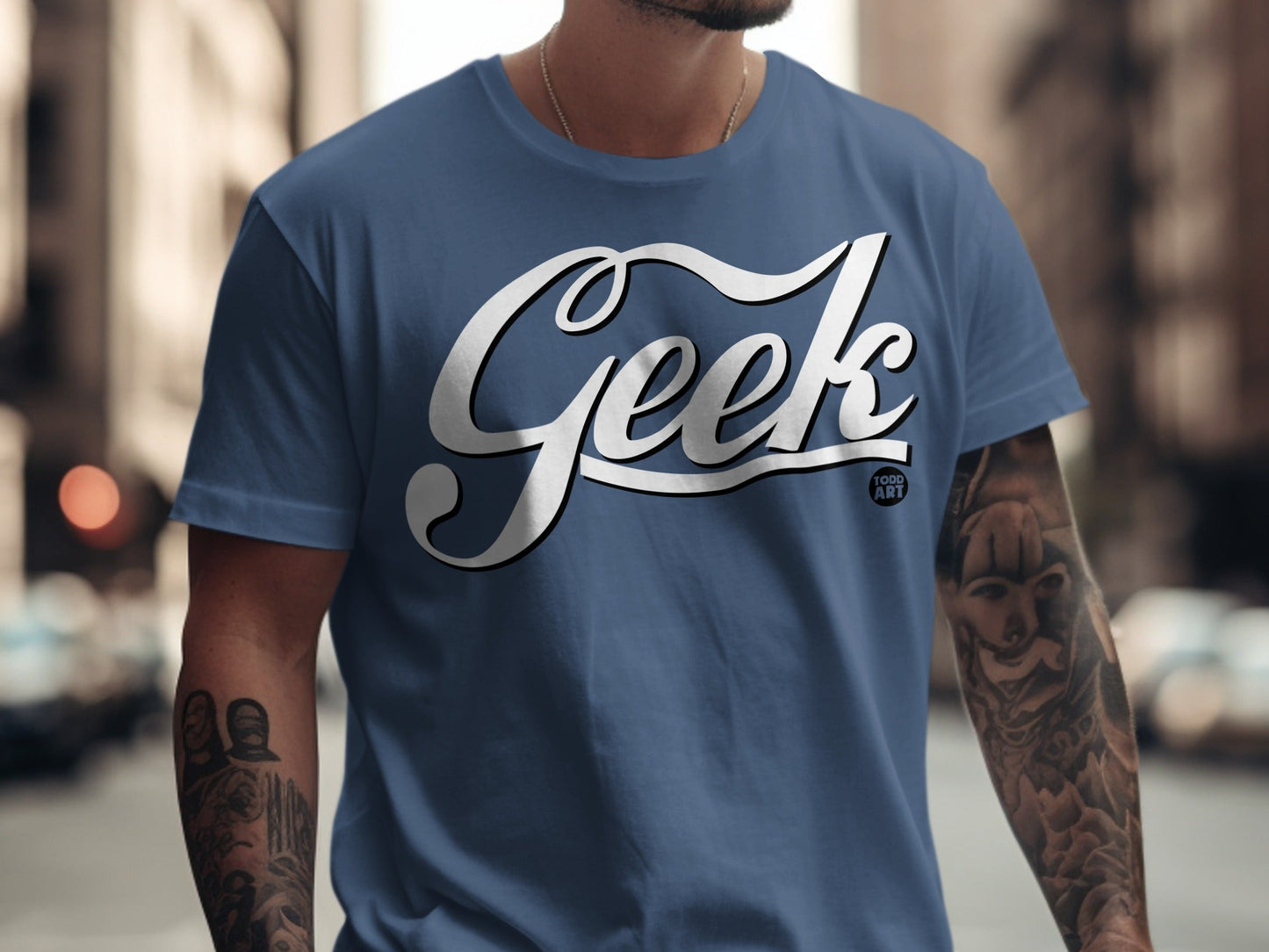 Blue t-shirt with white "Geek Food Art" text and tattooed arms.