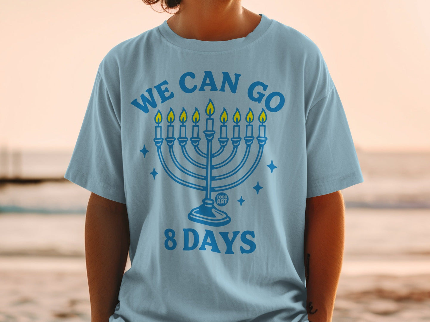 Light blue t-shirt with a menorah and "WE CAN GO 8 DAYS" text.