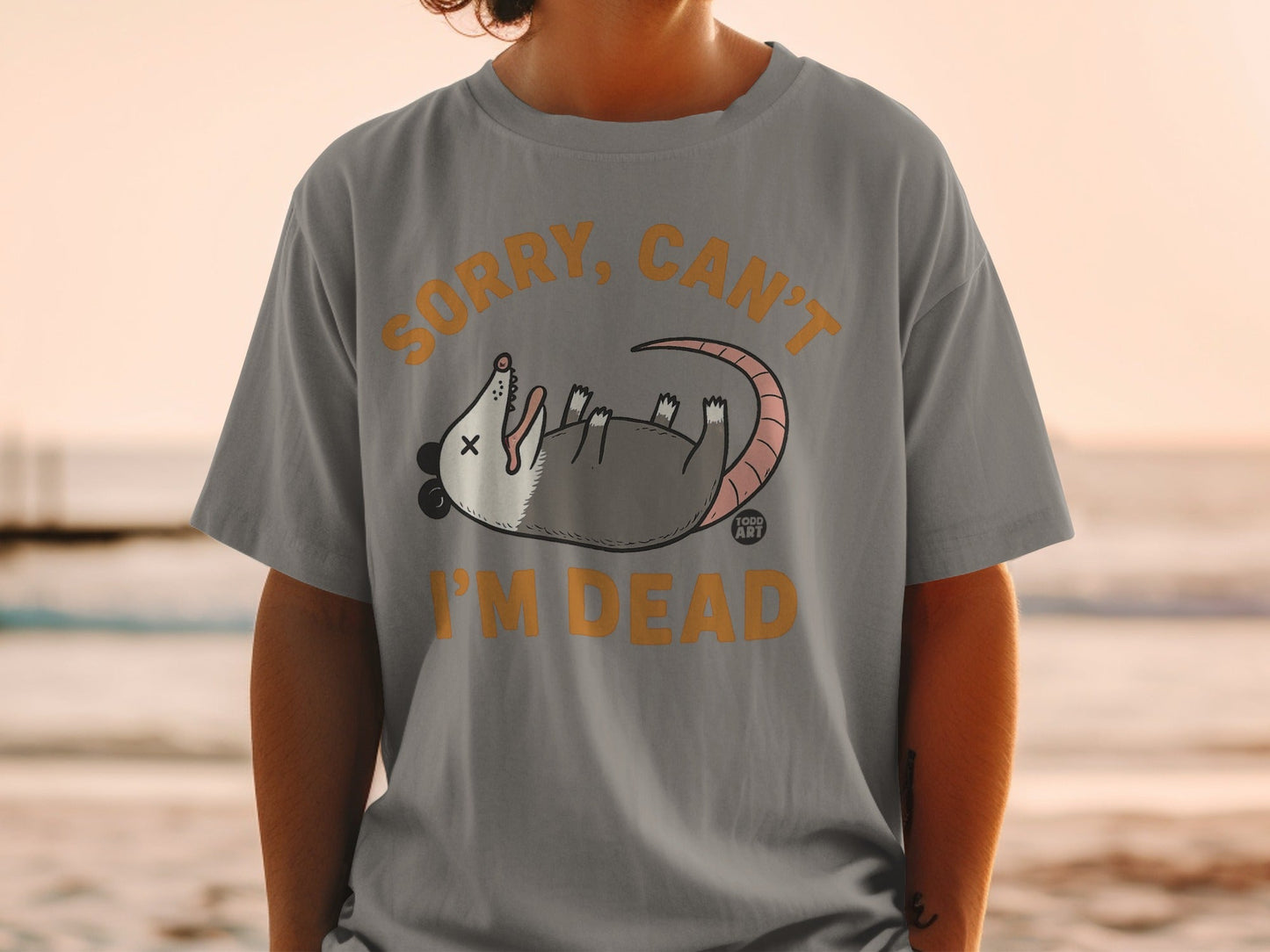 Gray t-shirt with cartoon possum and text "Sorry, Can't I'm Dead".