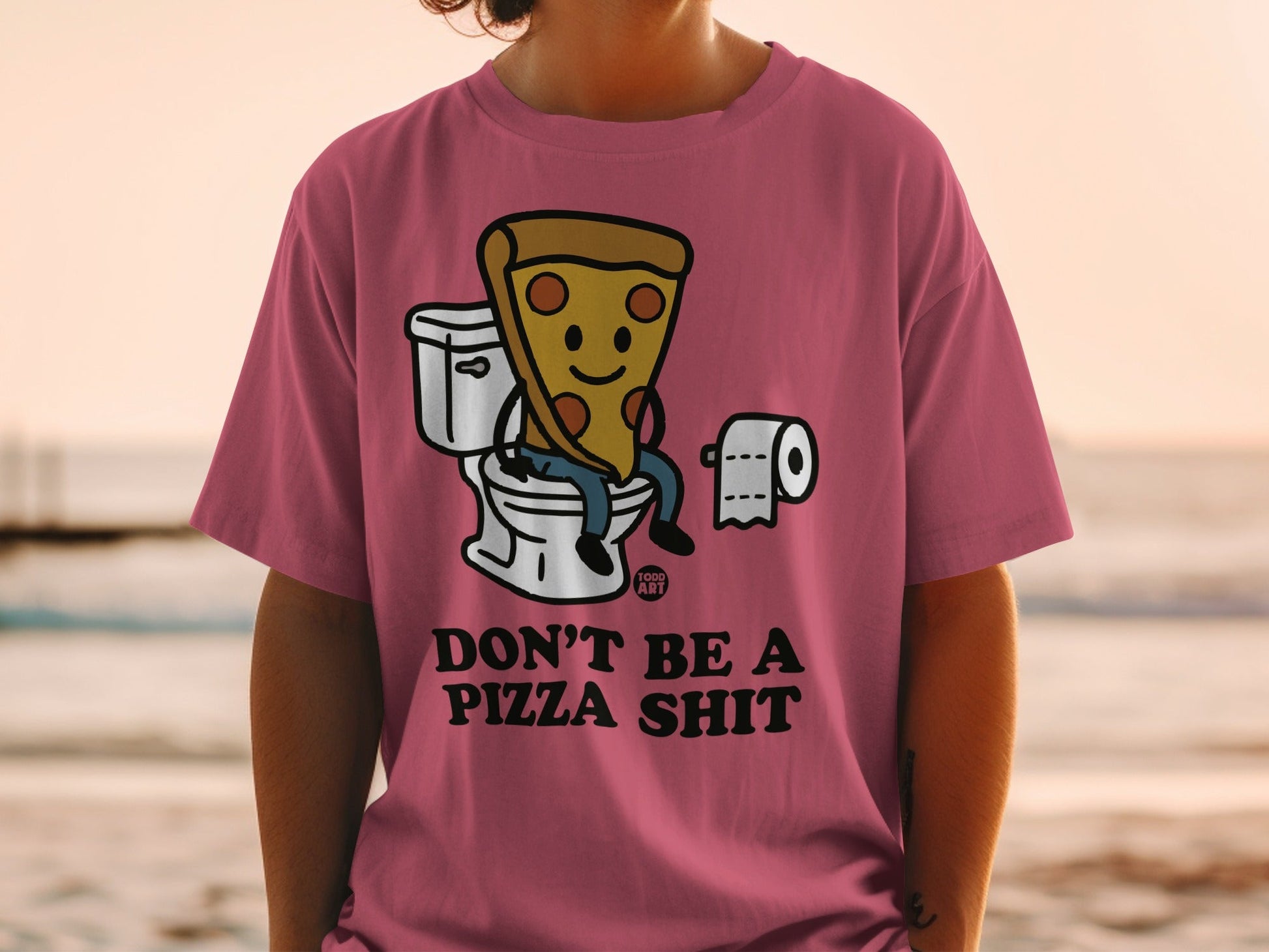 Pink t-shirt with a cartoon slice of pizza on a toilet, text reads "DON'T BE A PIZZA SHIT".
