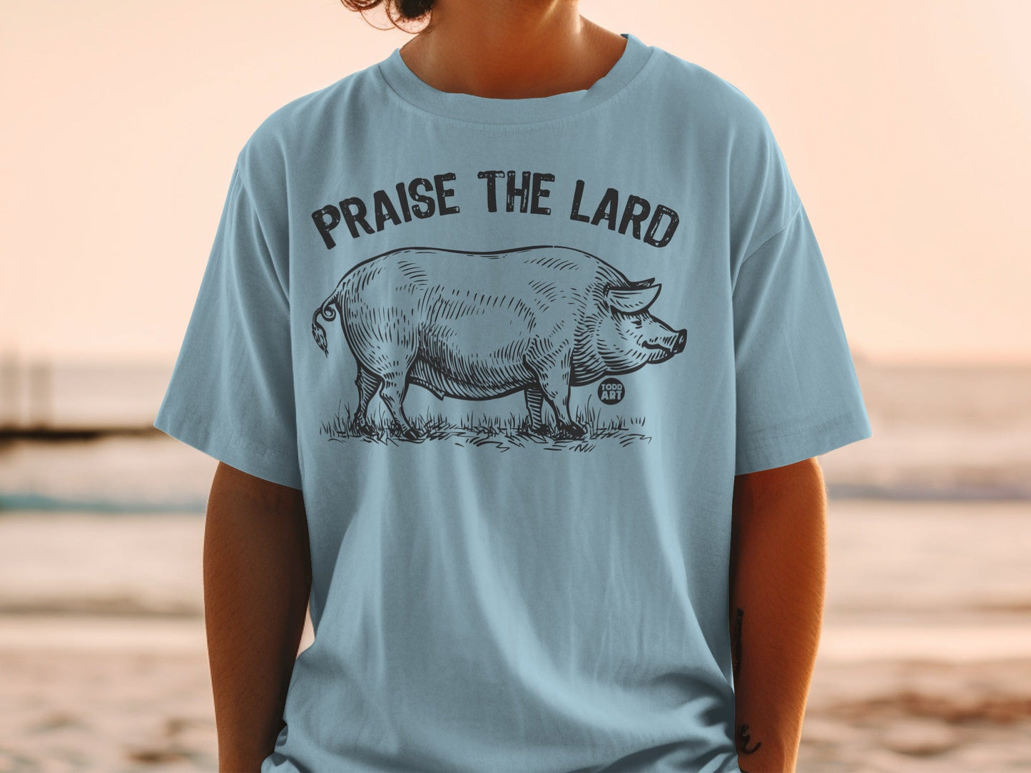 Light blue t-shirt with black sketch of a pig and "Praise the Lard" text.
