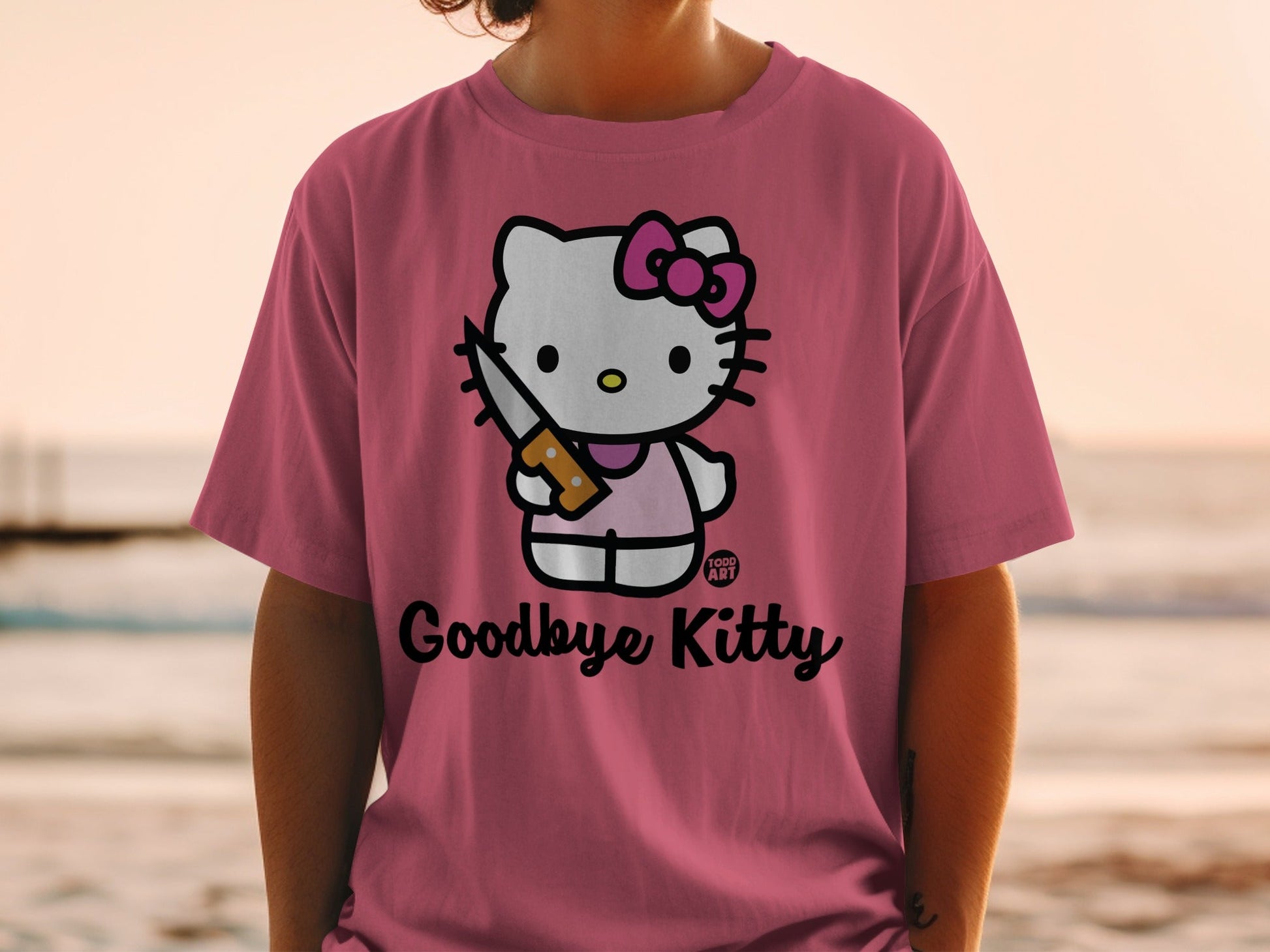 Hello Kitty wearing pink shirt holding knife, "Goodbye Kitty" text.