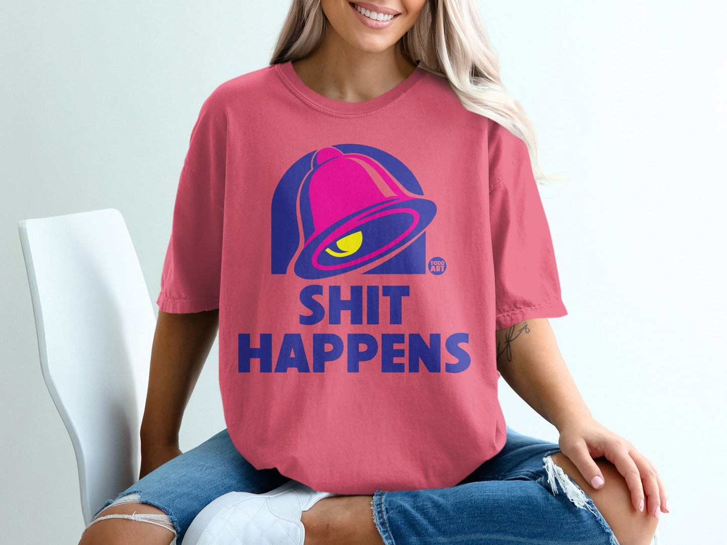 Pink t-shirt with blue "shit happens" text and Taco Bell bell logo.