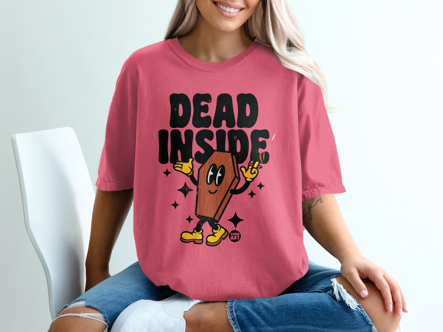 "Dead Inside" text with cartoon coffin character on pink t-shirt.